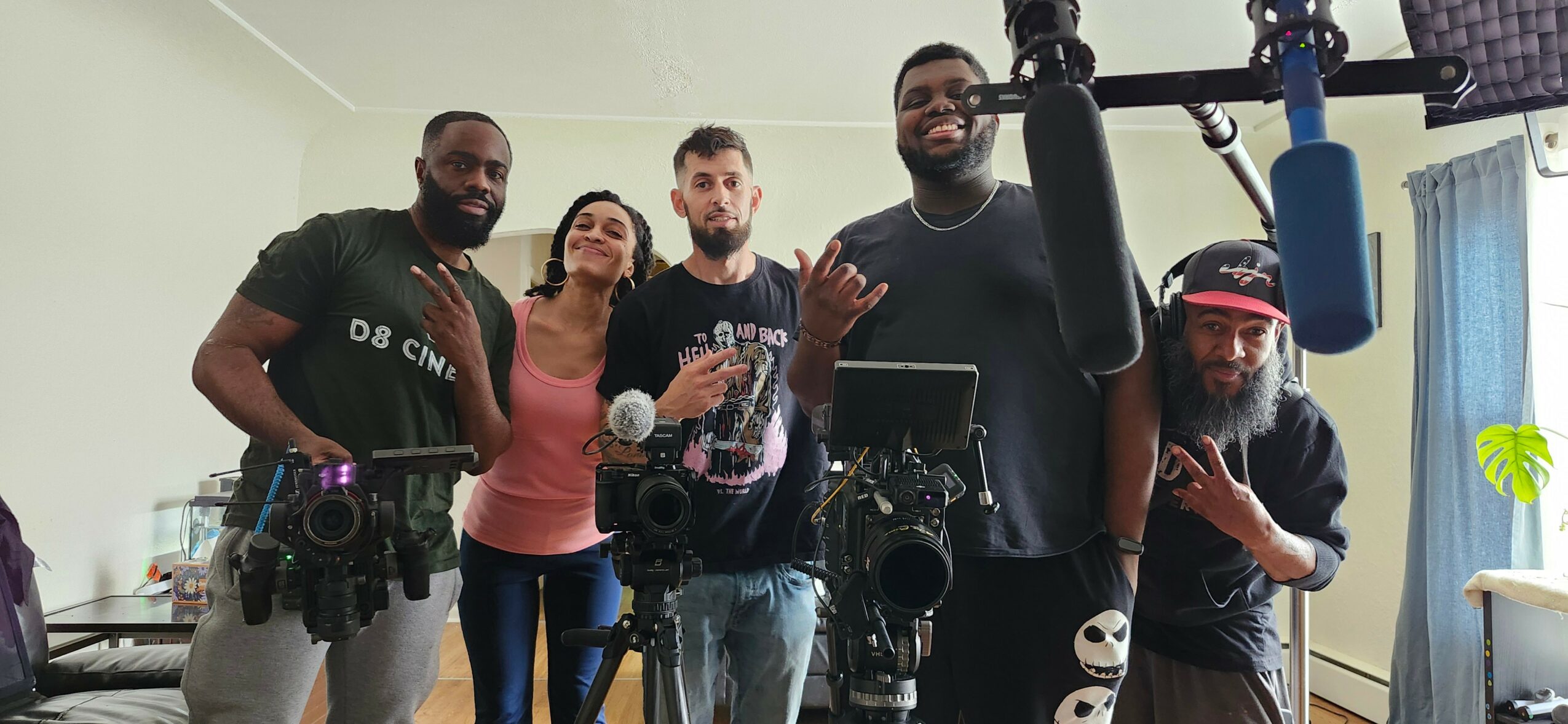 Group of five people in a room with camera equipment, smiling and posing for the photo.