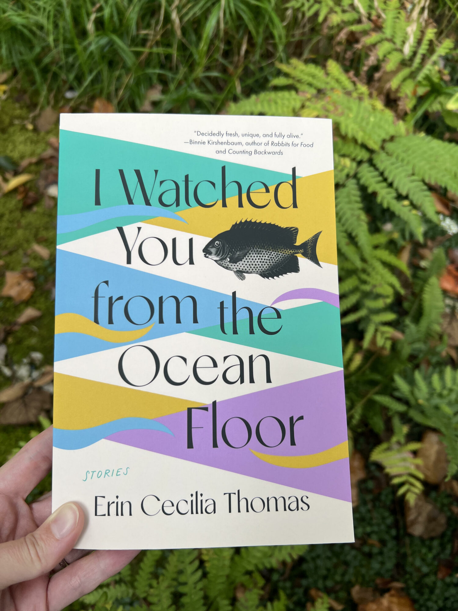 Book cover titled 'Watched You from the Ocean Floor' with a fish illustration, colorful waves, and author's name Erin Cecilia Thomas.
