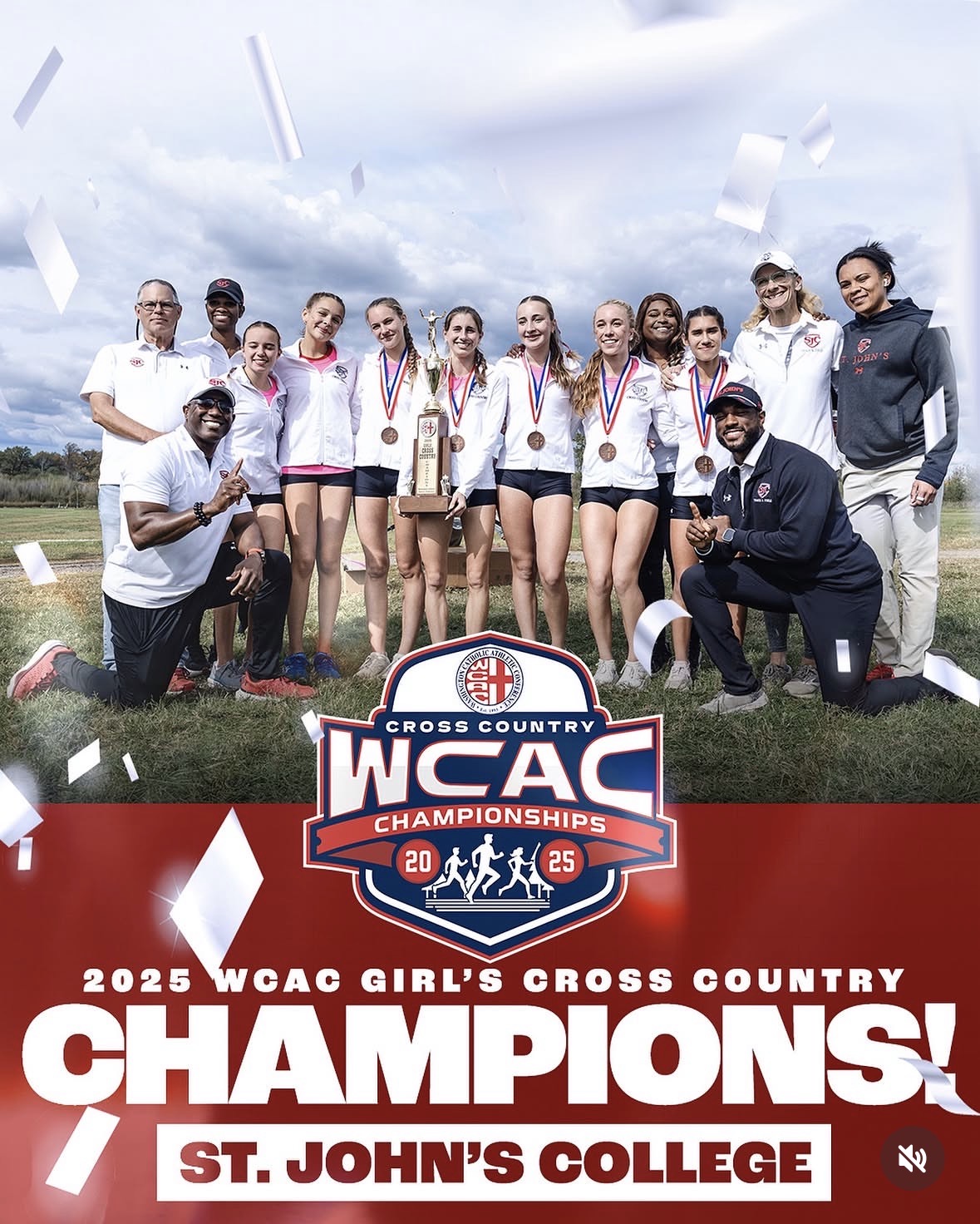 Group of female cross country runners and coaches celebrating with medals and trophy outdoors, WCAC Champions banner, St. John's College, confetti falling, daytime.