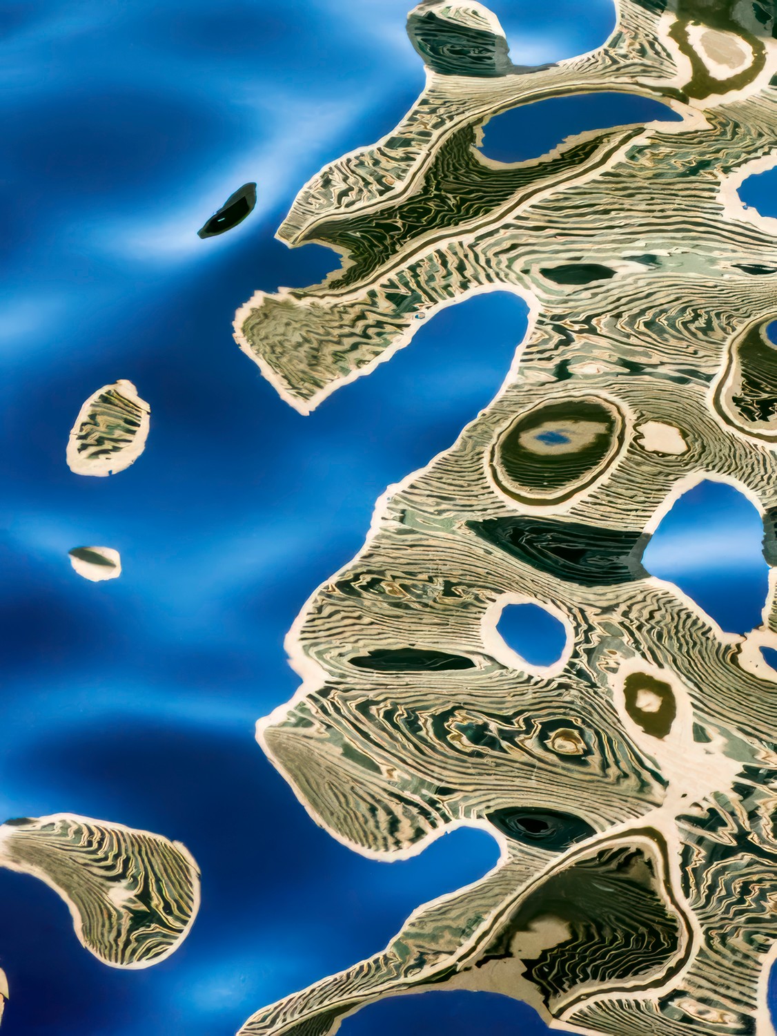 Reflected landscape with water and land formations, creating abstract patterns and shapes.