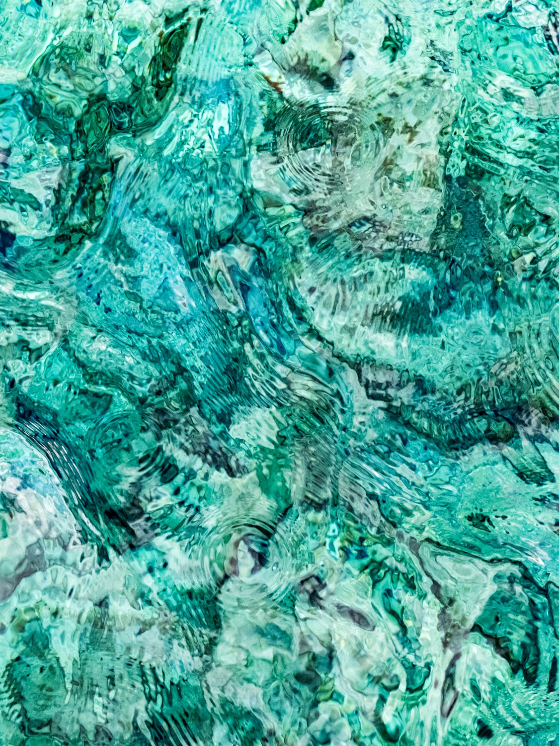 Abstract textured artwork with shades of blue and green, featuring a faint face and various patterns.