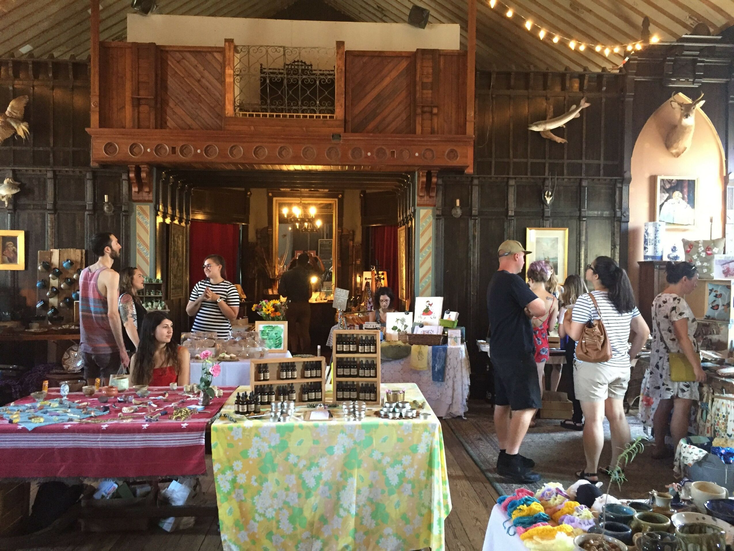 People browsing items in a store with wooden furniture and shelves, colorful displays, and warm lighting.