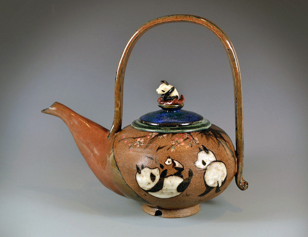 Ceramic teapot with a curved handle, decorated with painted ducks and a small duck figurine on the lid.