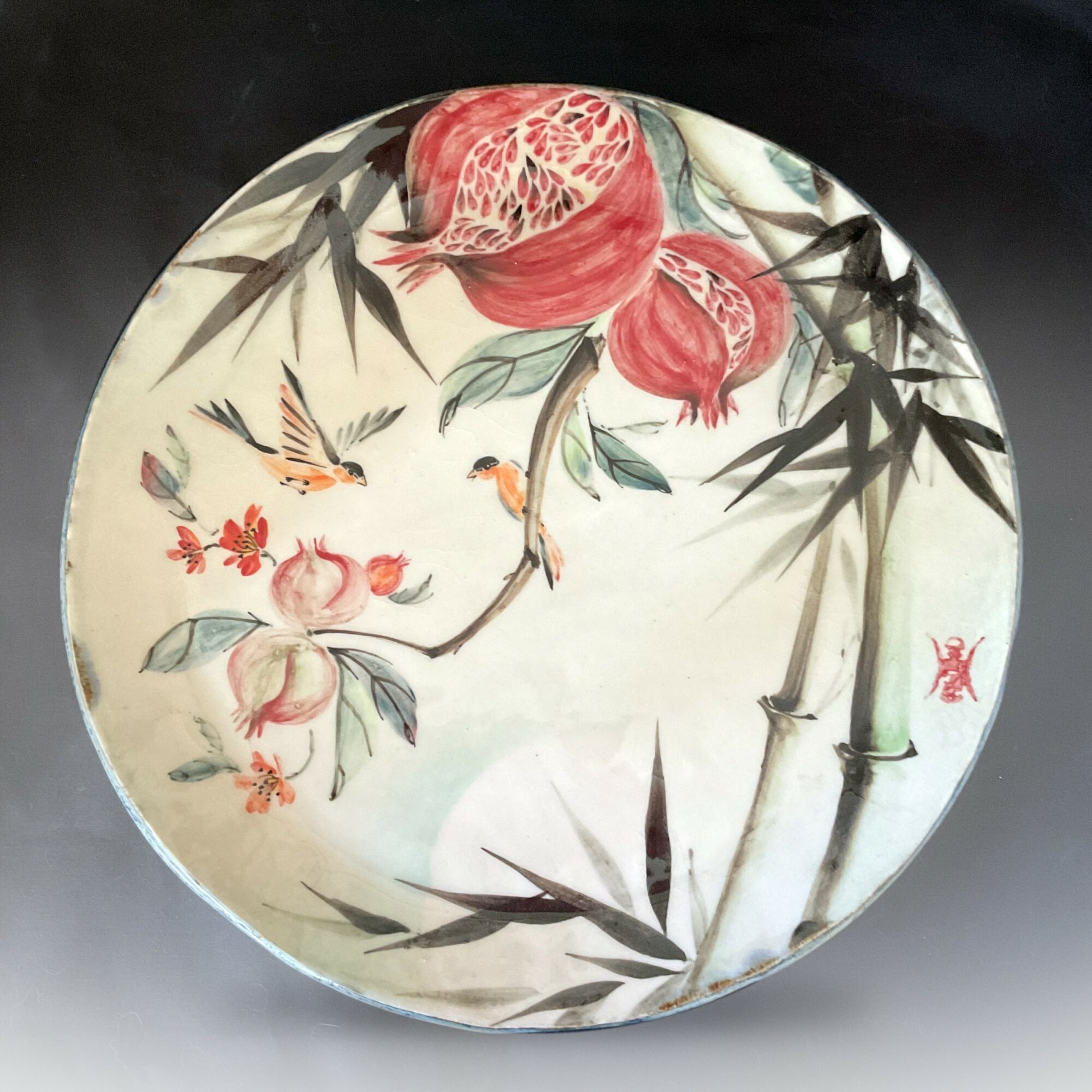 Decorative round plate with pomegranate, bamboo, and hummingbirds in traditional Asian style, watercolor painting.