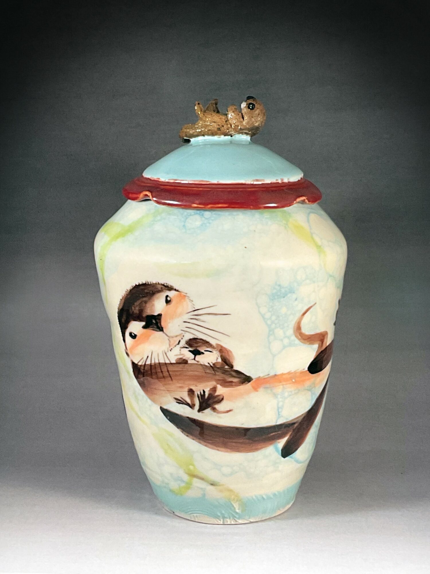 Decorative vase with a cat and mouse design, featuring a mouse on the lid, against a dark background.