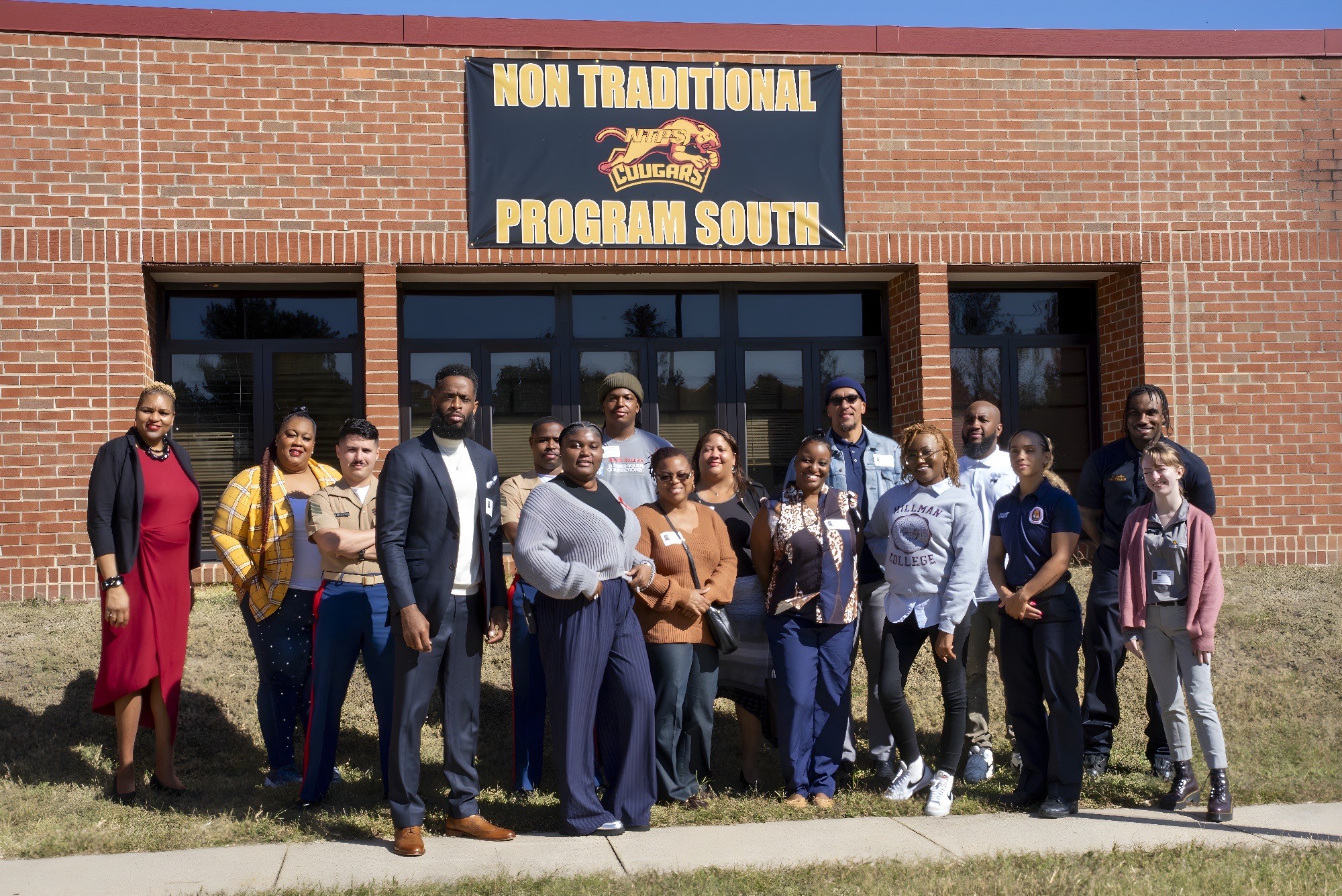 Group of people standing outside a brick building with a sign that reads 'Non Traditional Program South'.