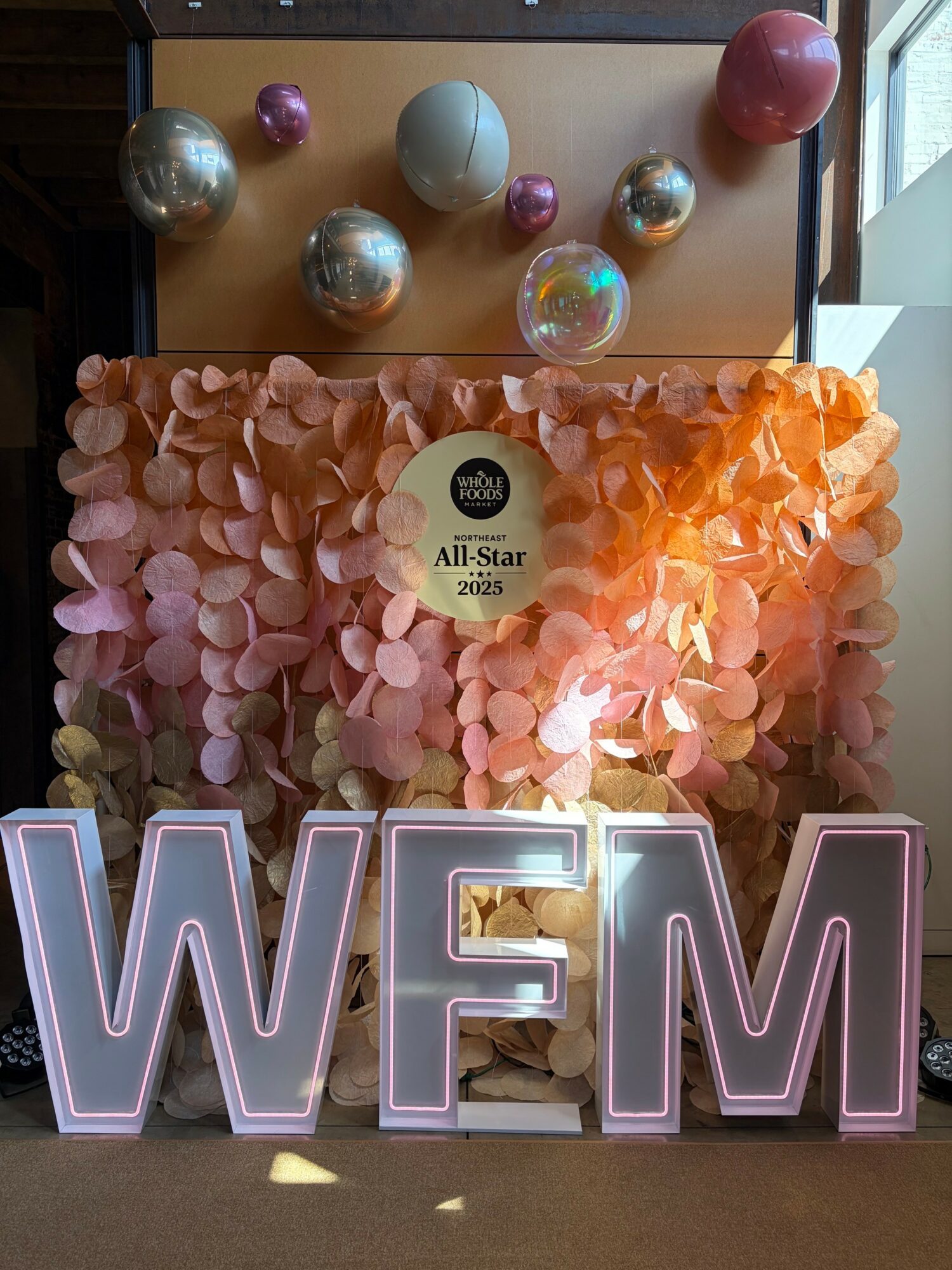 Decorative display with pink and metallic balloons, illuminated