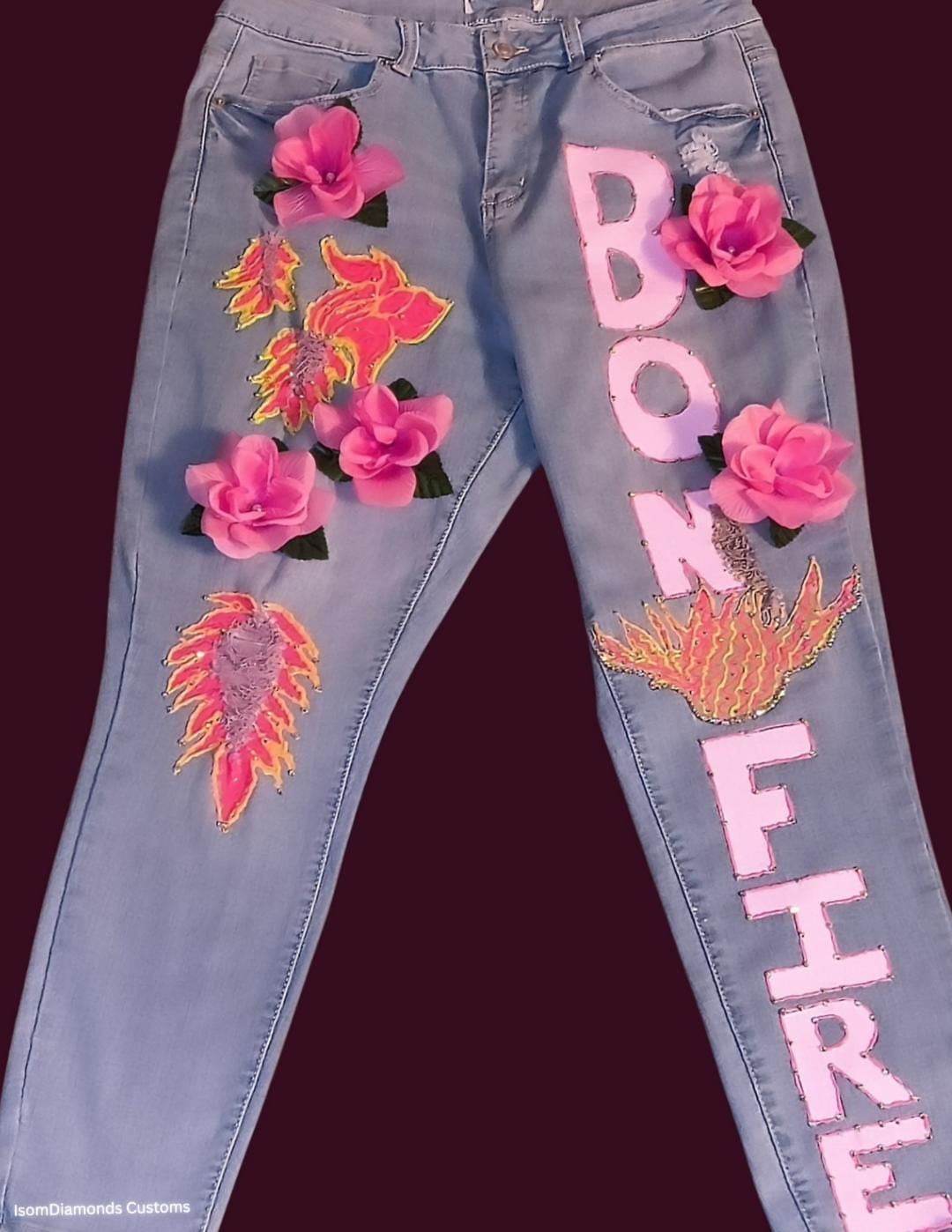 Jeans with floral embroidery and pink fabric flowers, featuring the words 'BONFIRE' in large pink letters.