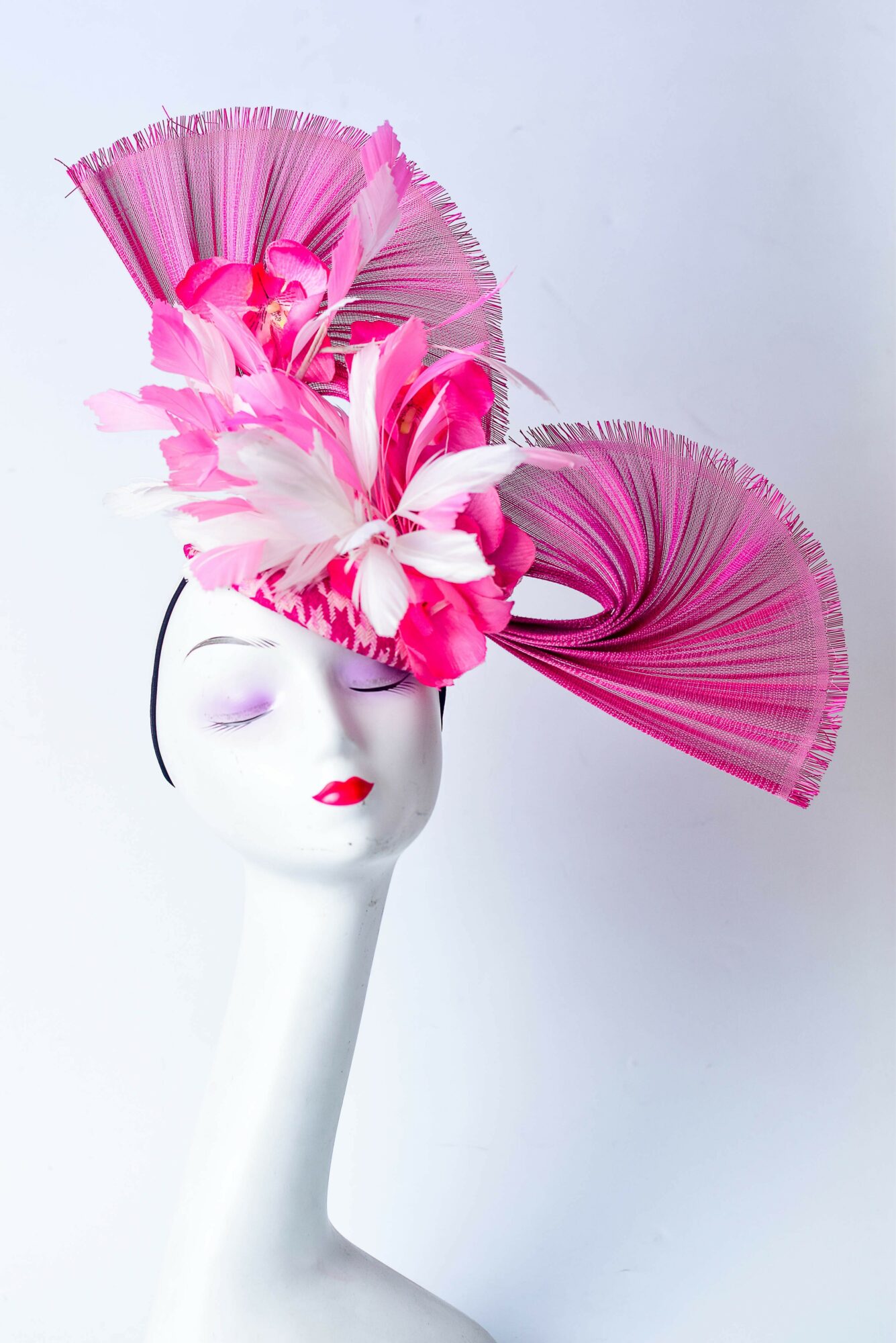 White mannequin head with pink and white floral headpiece, against a plain light background.
