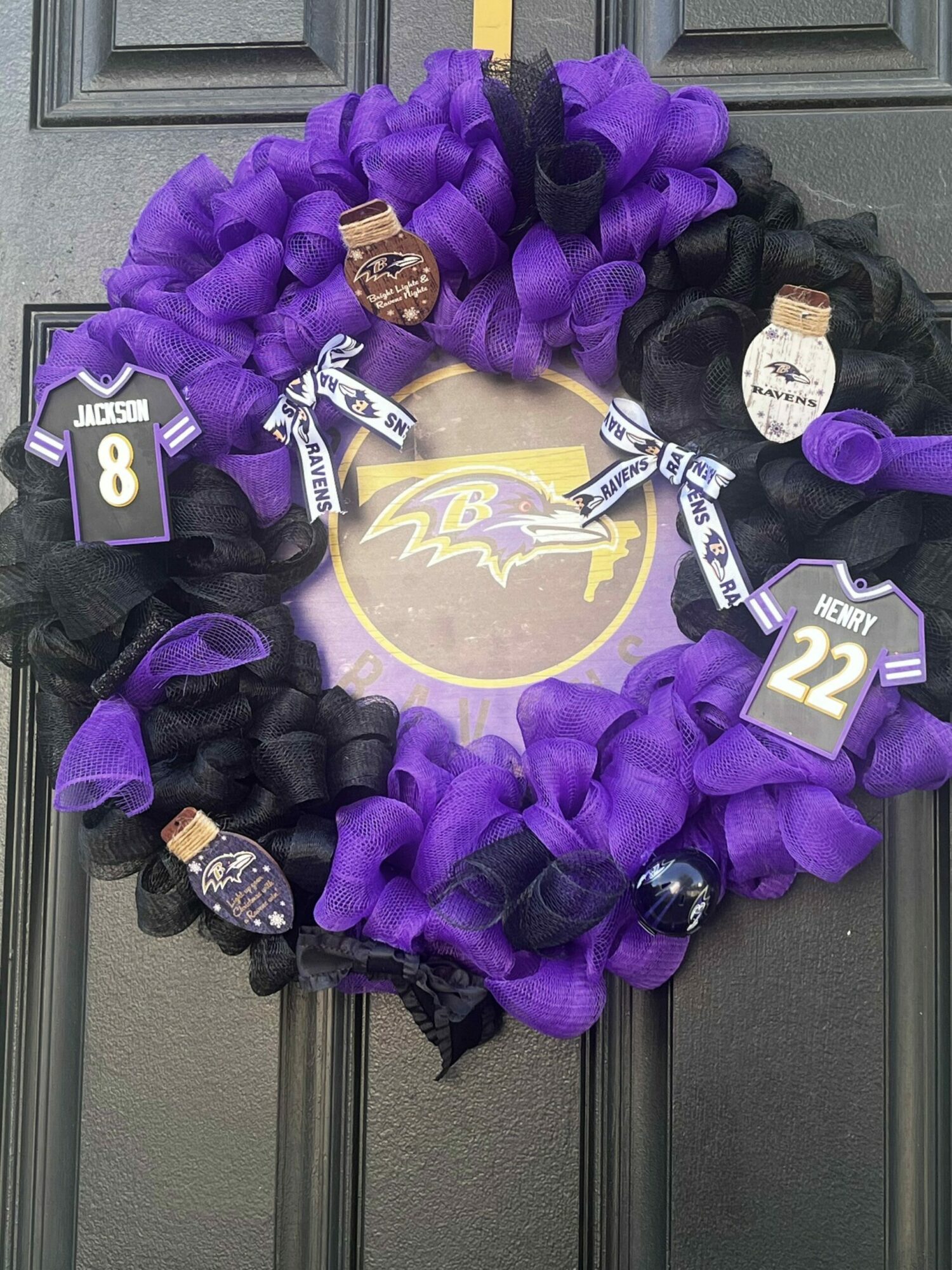 Purple and black wreath with Ravens-themed decorations and a circular emblem in the center.
