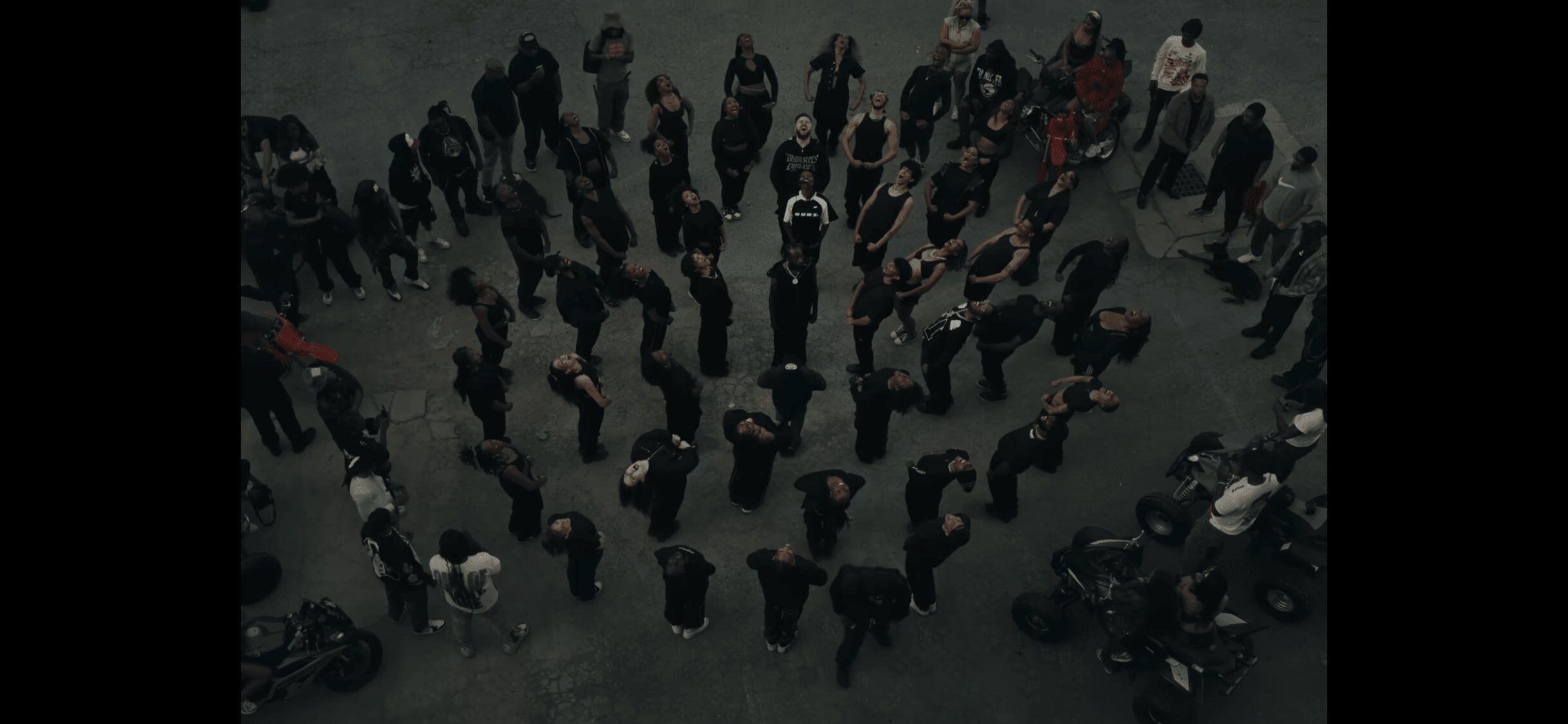 People standing in a circle on a dark surface, viewed from above.