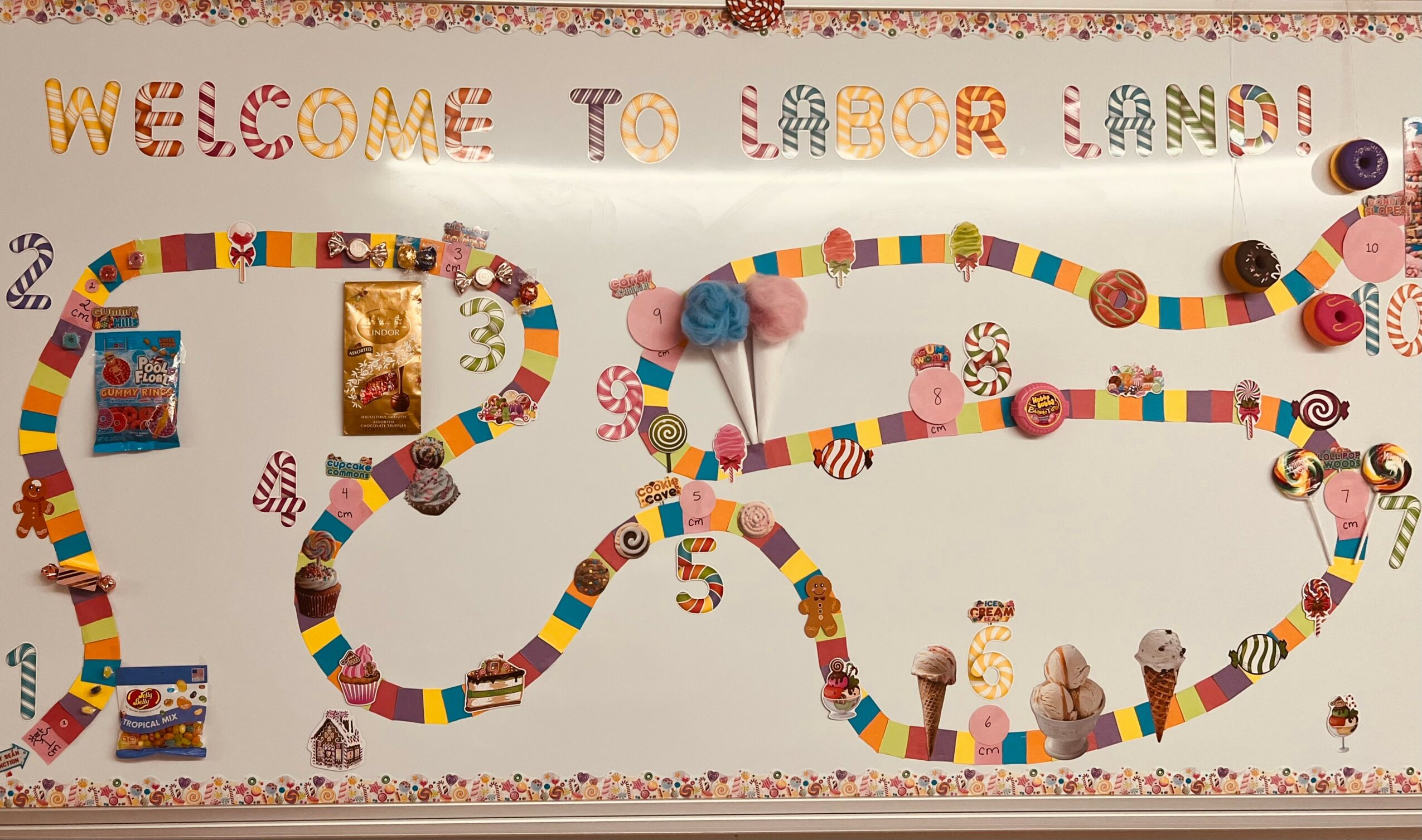 Colorful, winding paper chain with small pig and animal figures, greeting text, and decorative border on a white background.