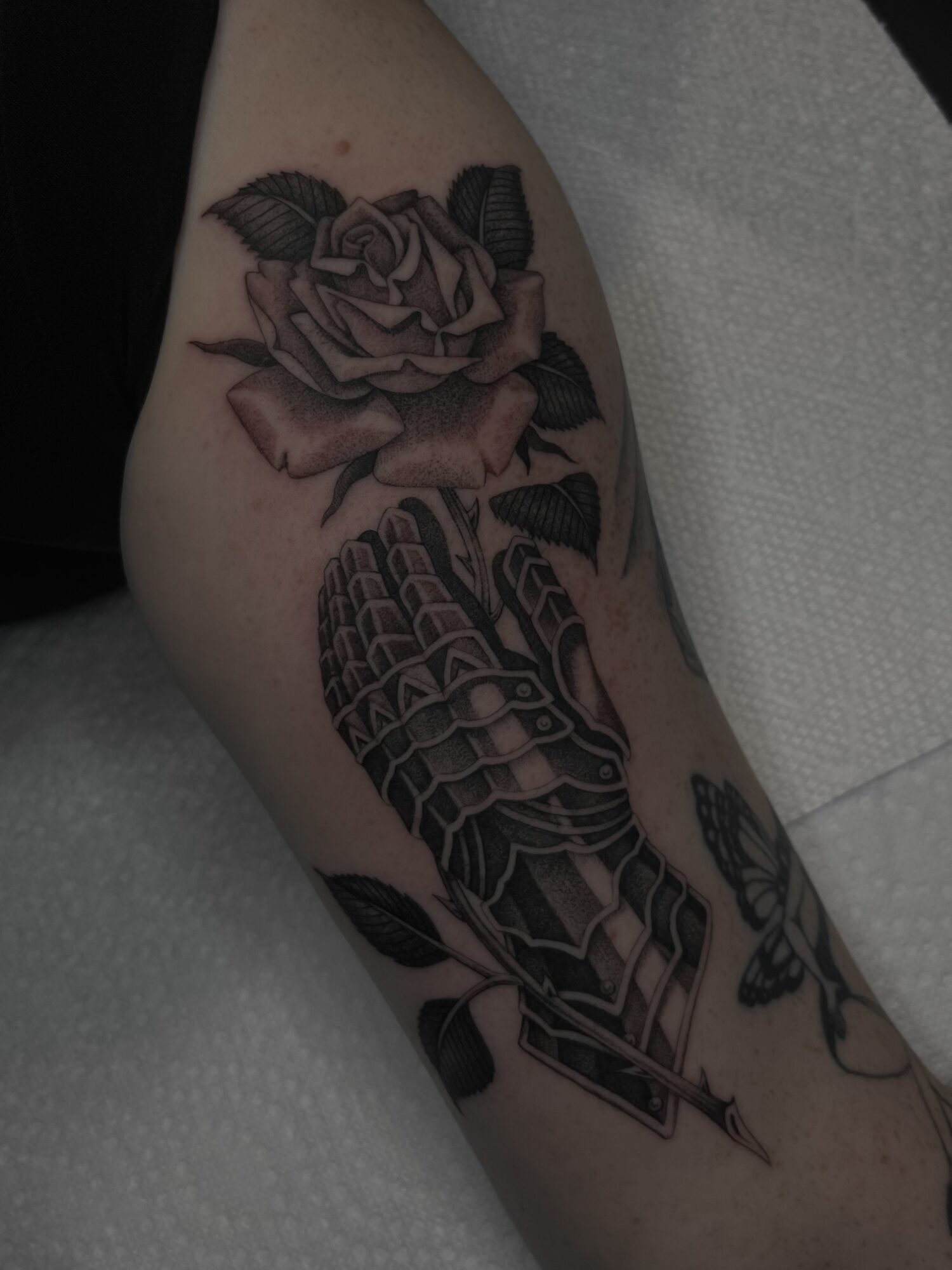 Tattoo of a rose and a snake on a person's arm, with detailed shading and black ink.
