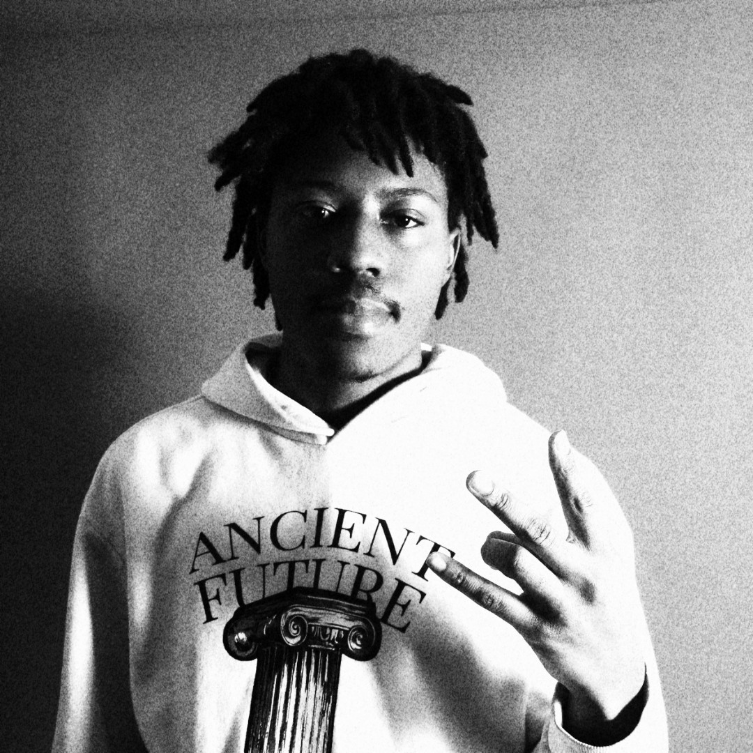 Young person with dreadlocks wearing a hoodie with text and a column illustration, making a hand gesture, in black and white.