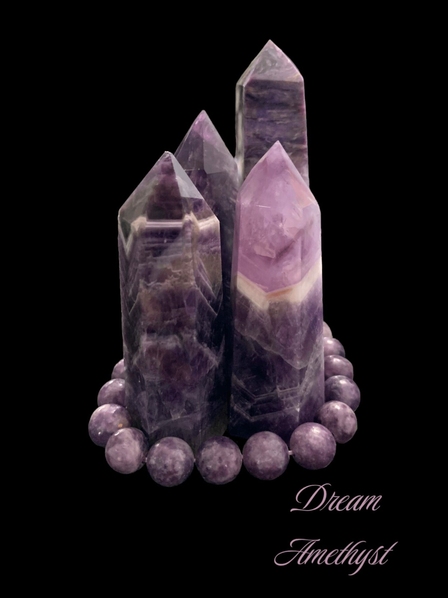 Four purple and gray amethyst crystal points surrounded by small spheres, with the words 'Dream Amethyst' in cursive.