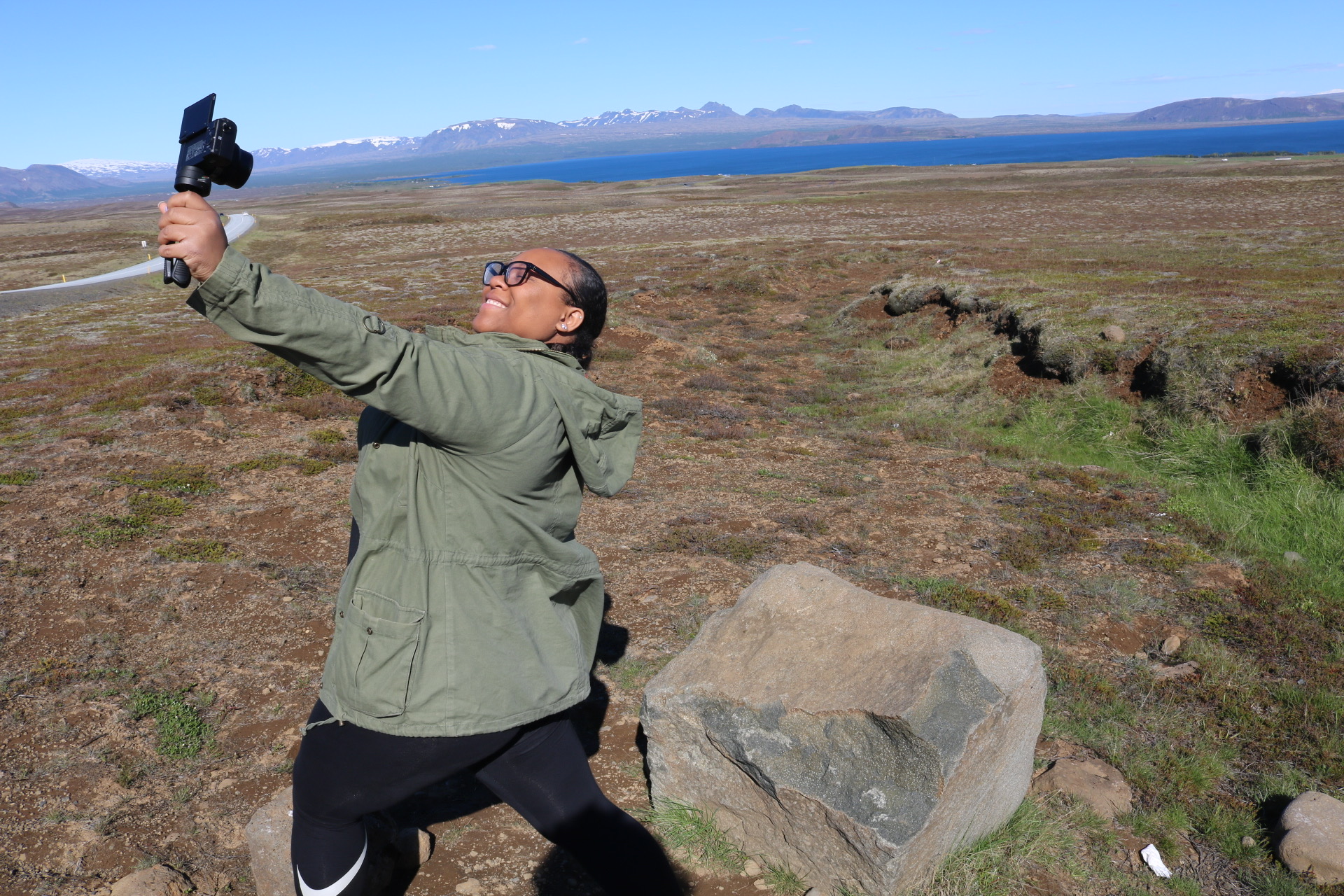 Person taking a selfie outdoors in a vast open landscape with mountains in the background.