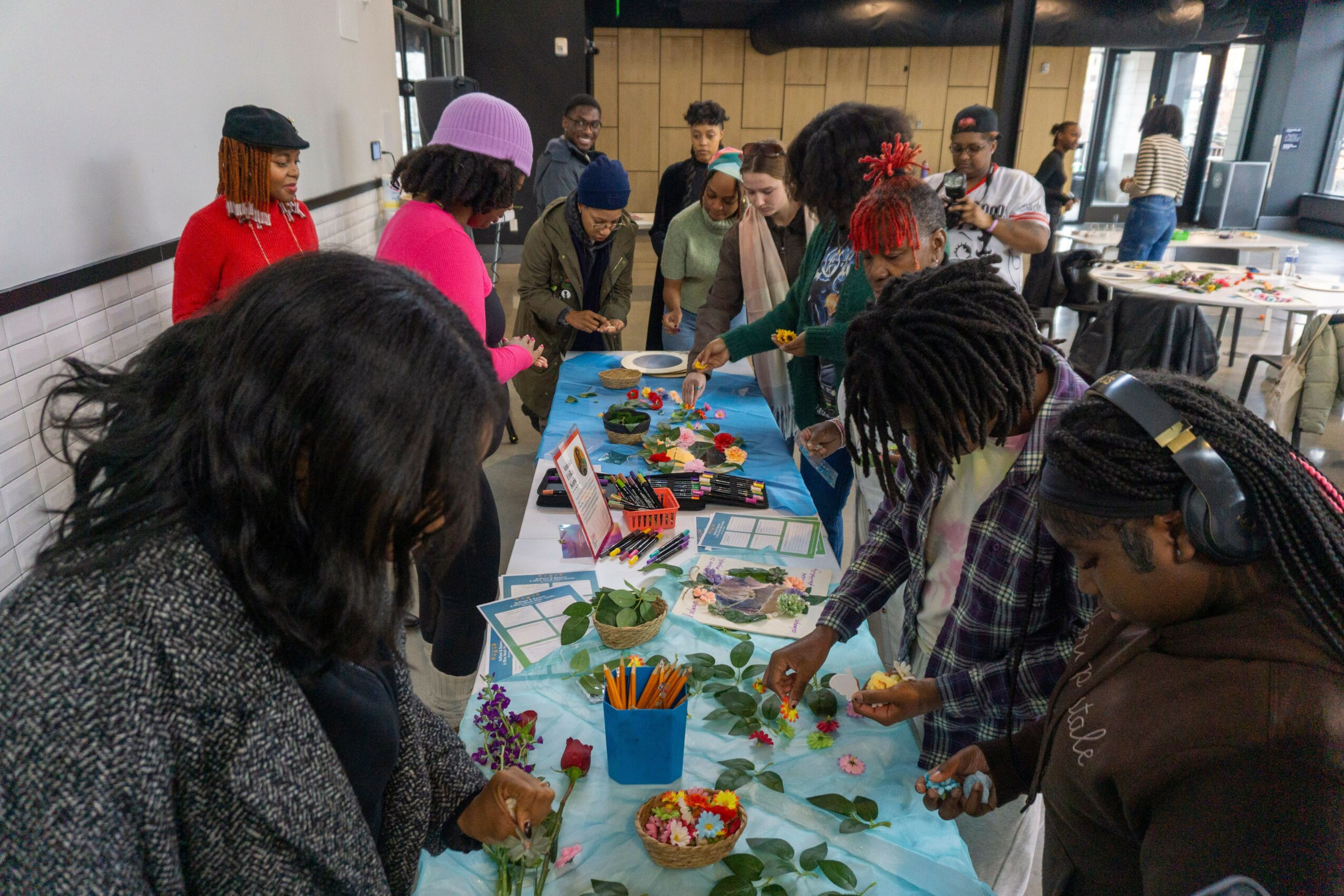 Group of people gathered around a table with craft supplies, working on a creative project indoors.
