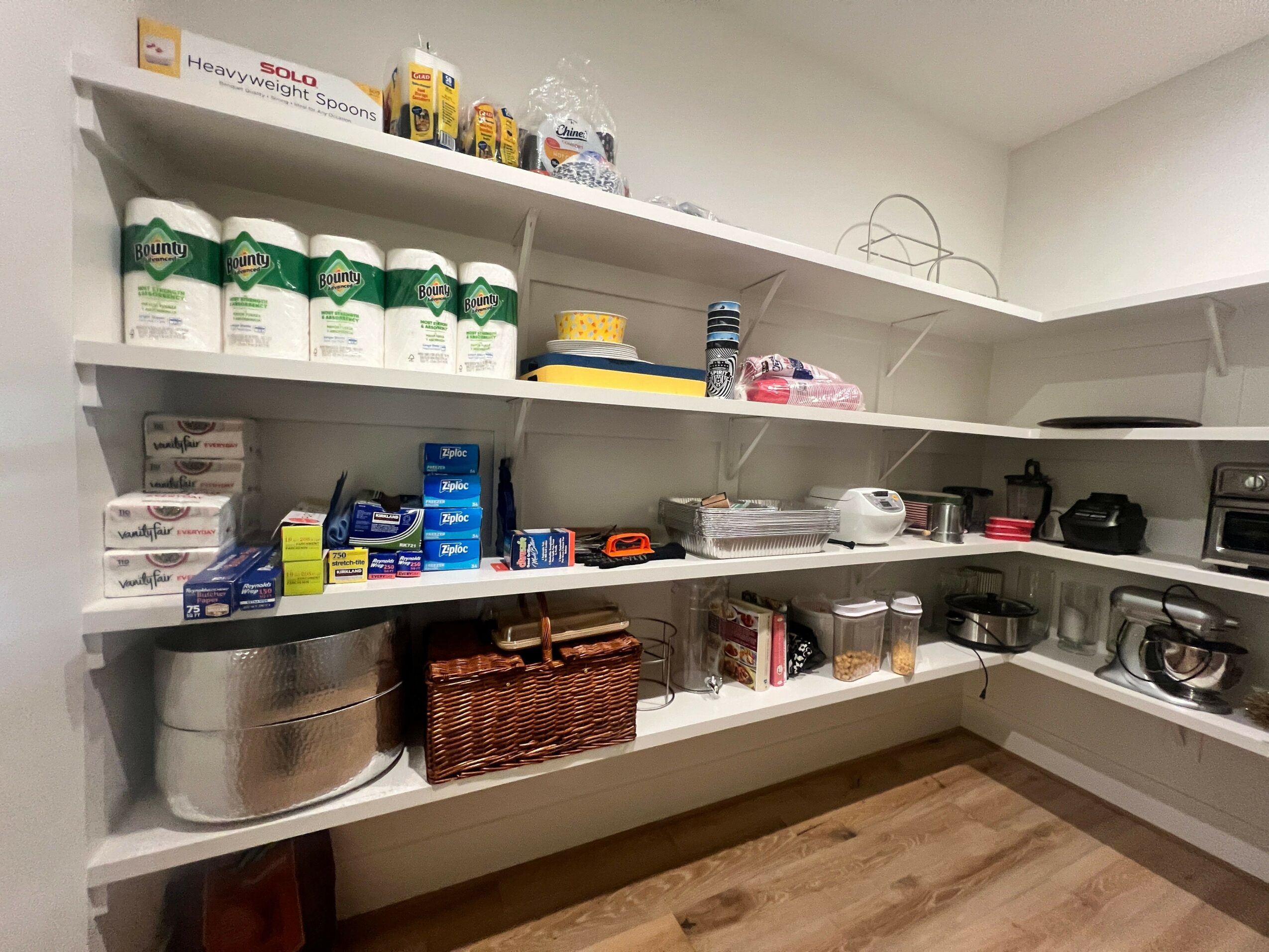 Shelves with various canned and boxed food items, containers, and kitchen supplies in a pantry, viewed from below.