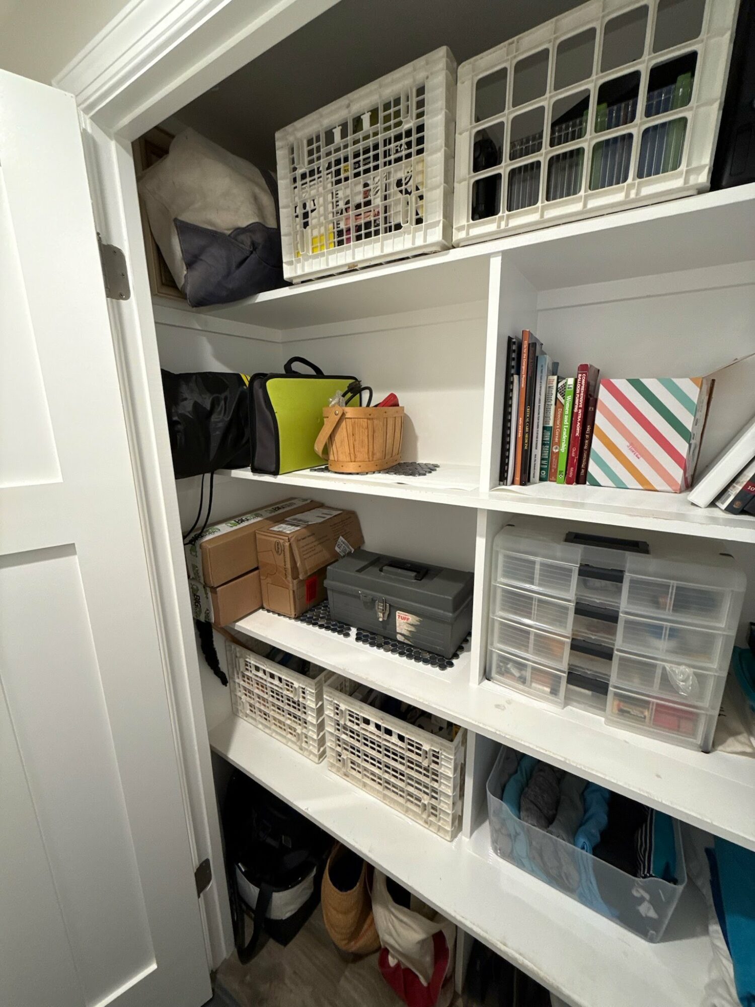 Closet shelf with storage bins, books, and boxes, organized on multiple levels.