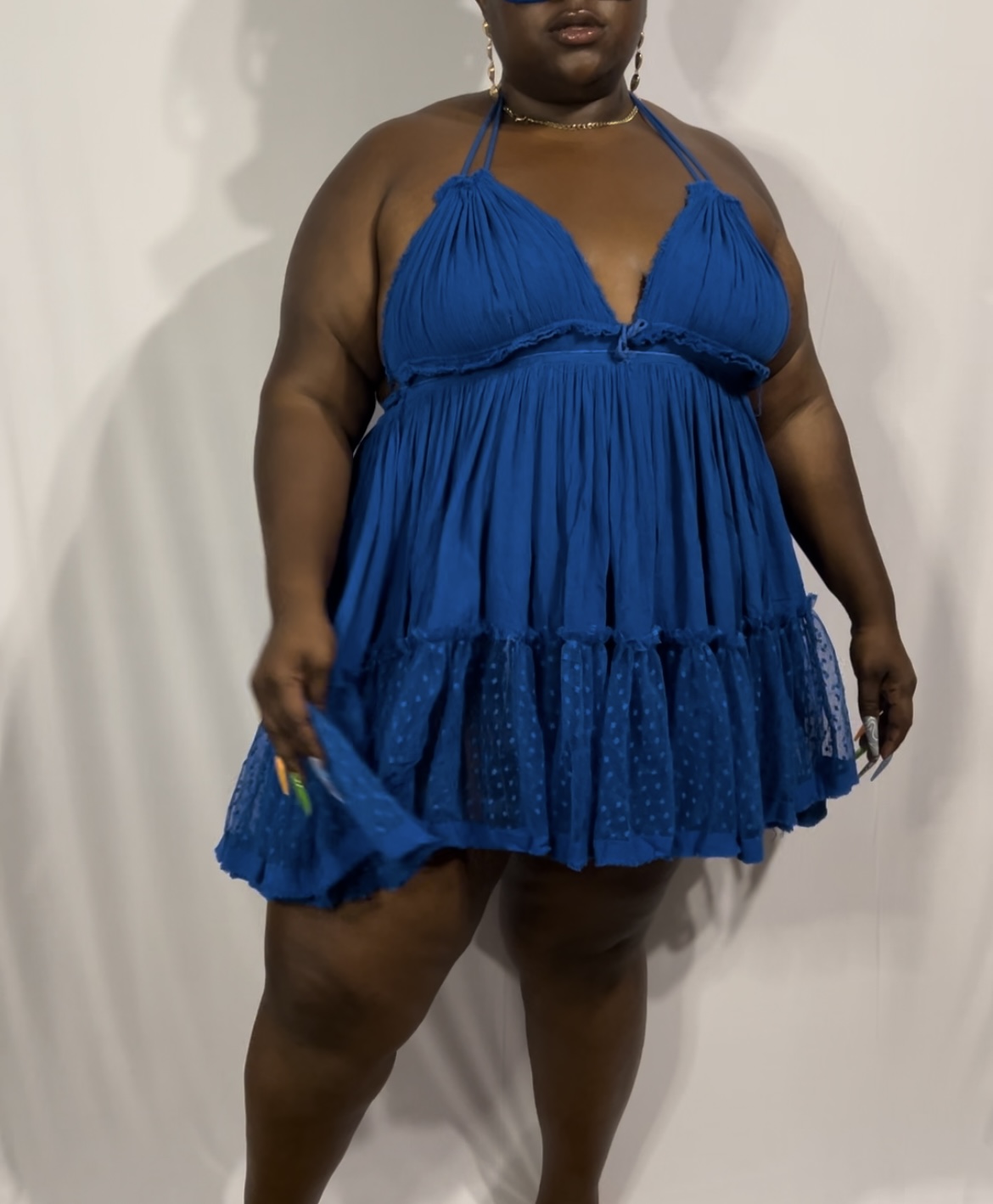 Person wearing a blue dress with ruffles, standing against a plain background.