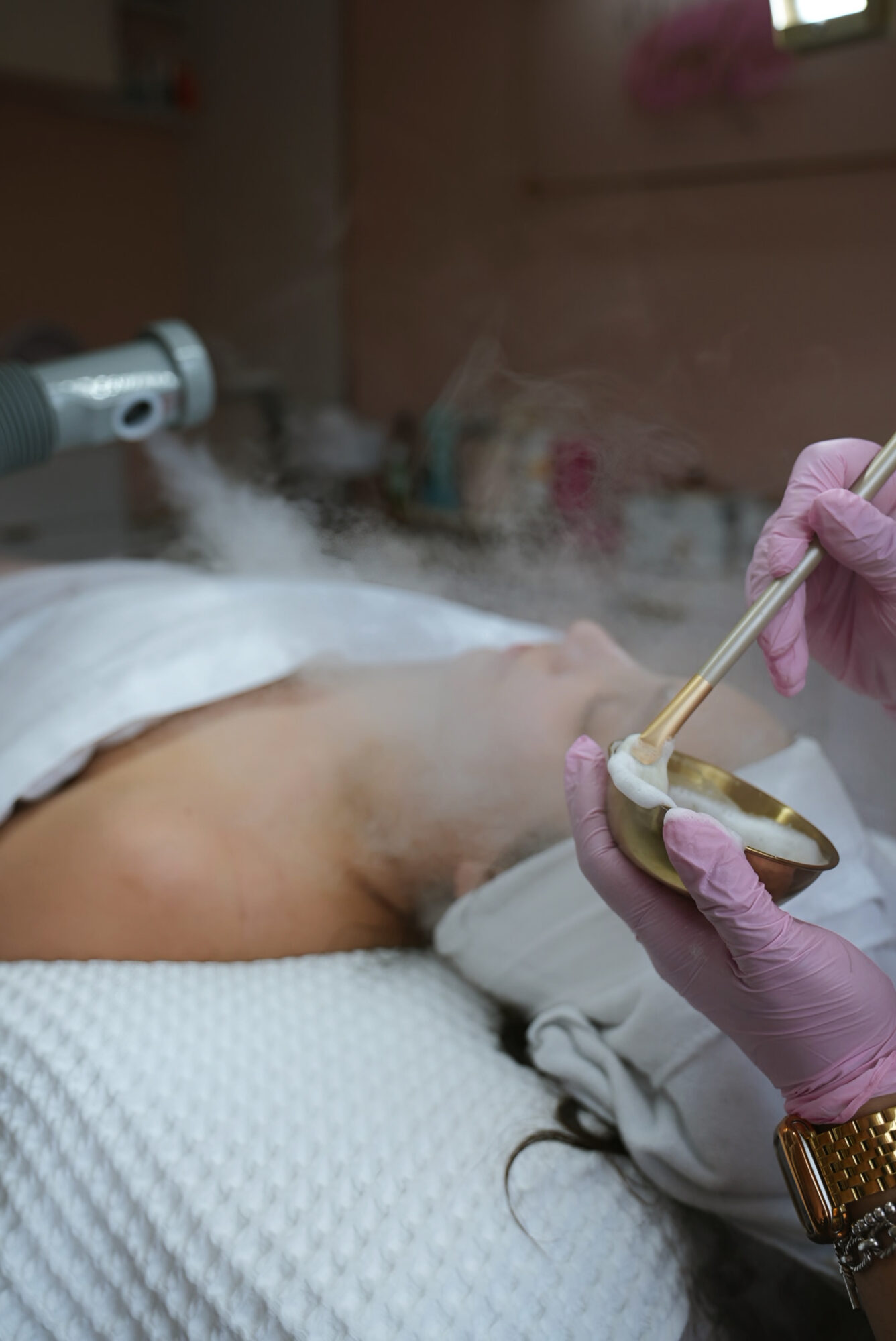 Person receiving medical treatment in a hospital bed, with a healthcare worker applying a substance with a brush.