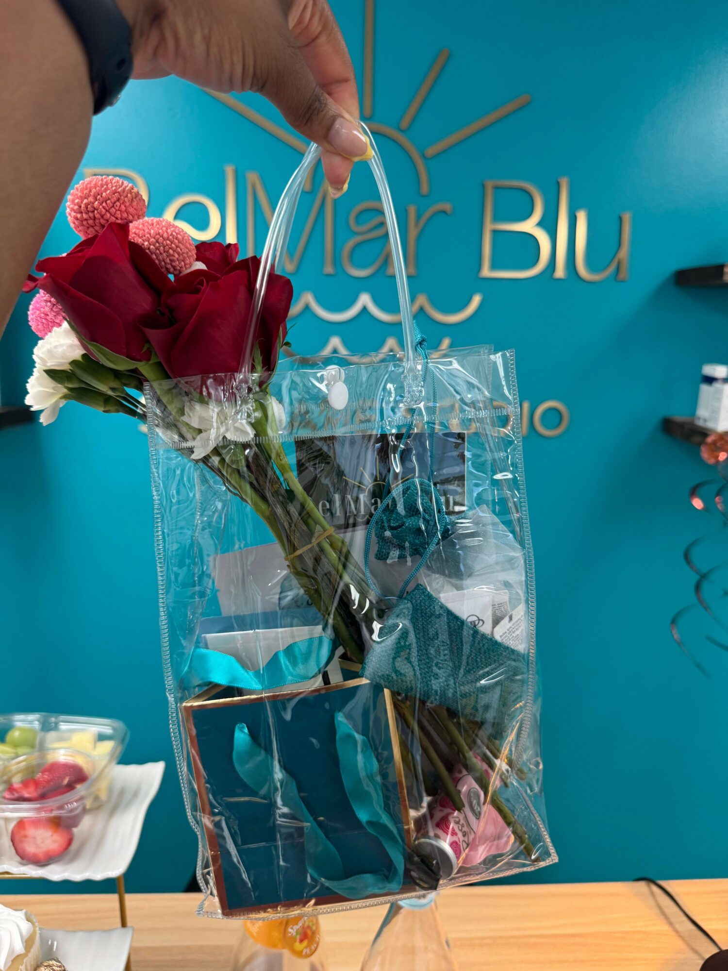 Person holding a wrapped bouquet of red and pink flowers in plastic wrap, with a blue background and text.
