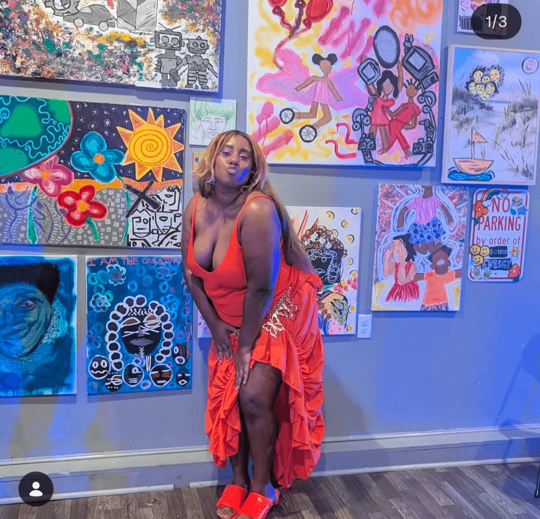 Woman in red dress and high heels poses in front of colorful artwork on gallery wall.