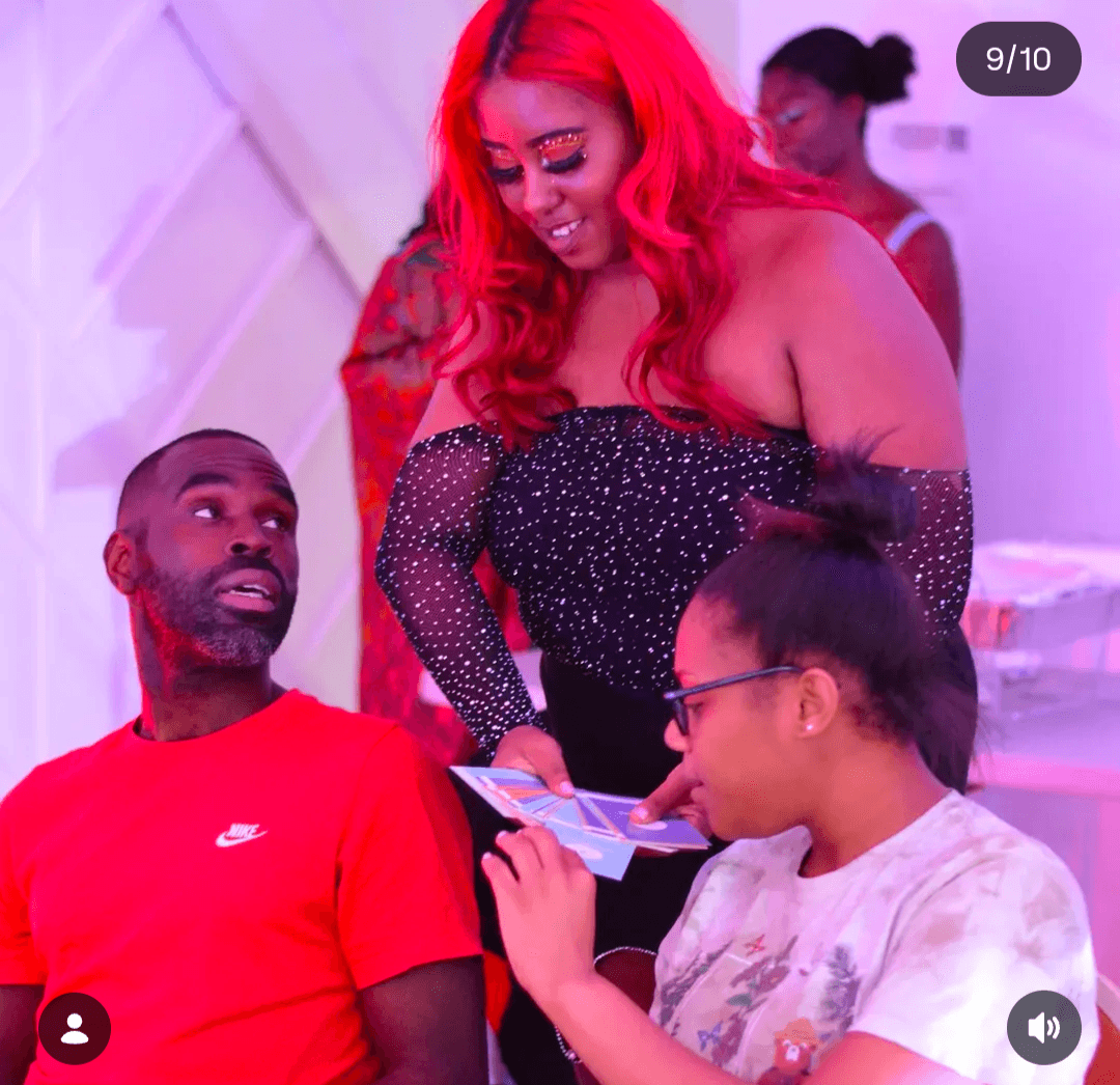 Three people at an event, one woman with bright red hair, two men, one with glasses, engaging with a phone.