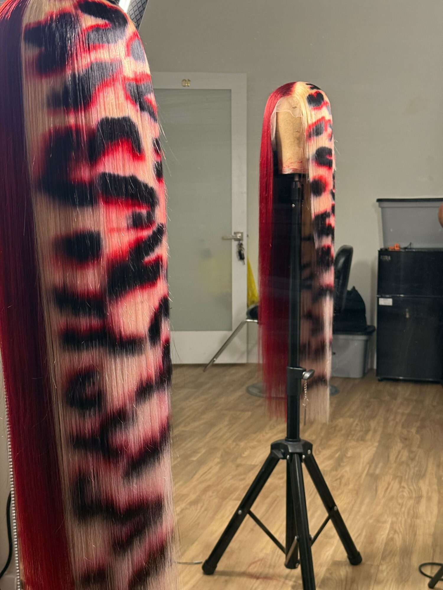 A close-up of a fabric with a red, black, and beige leopard print pattern, draped over a surface.