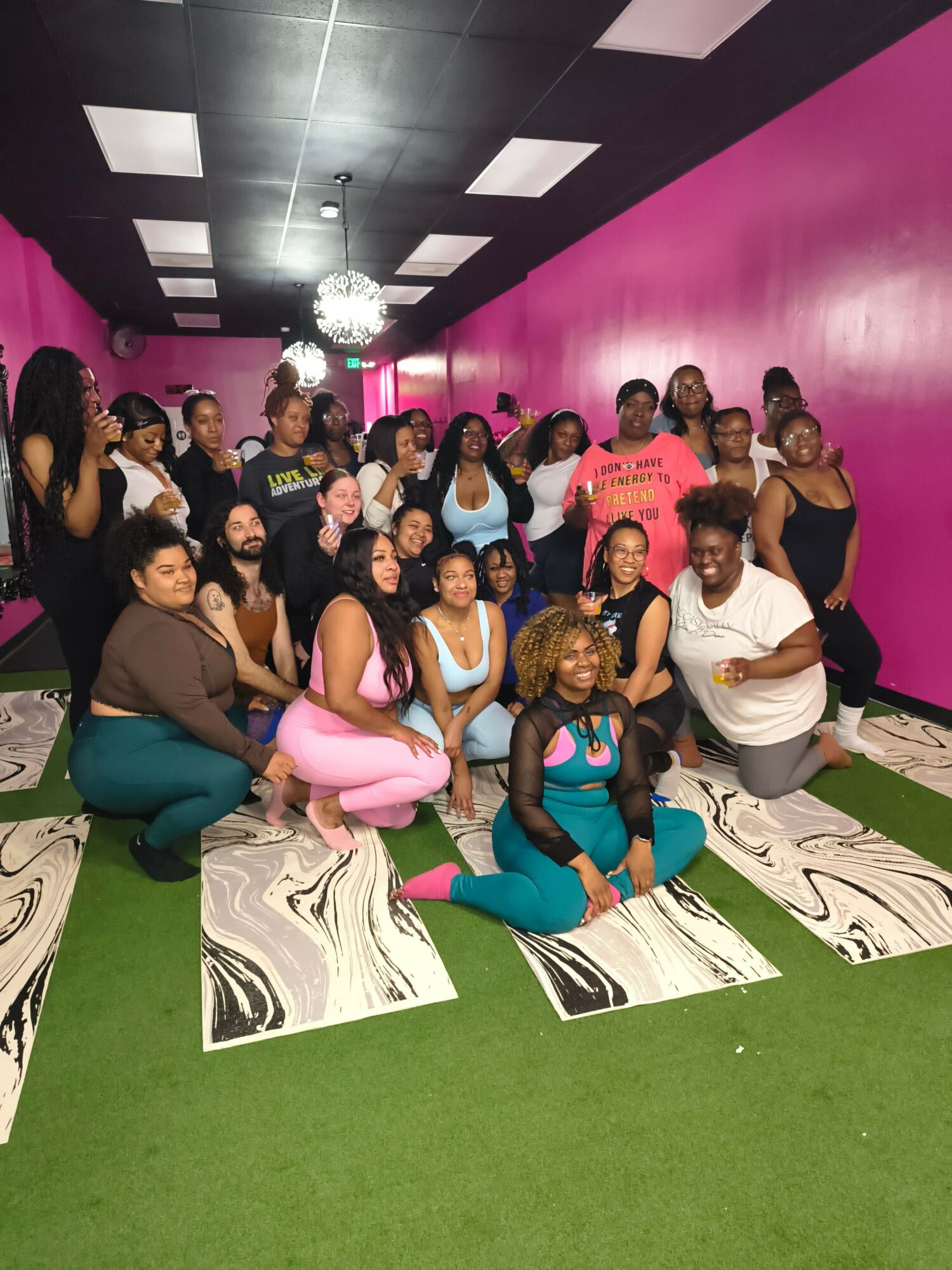 Group of women and children sitting and standing on a patterned bench in a room with pink and green walls.
