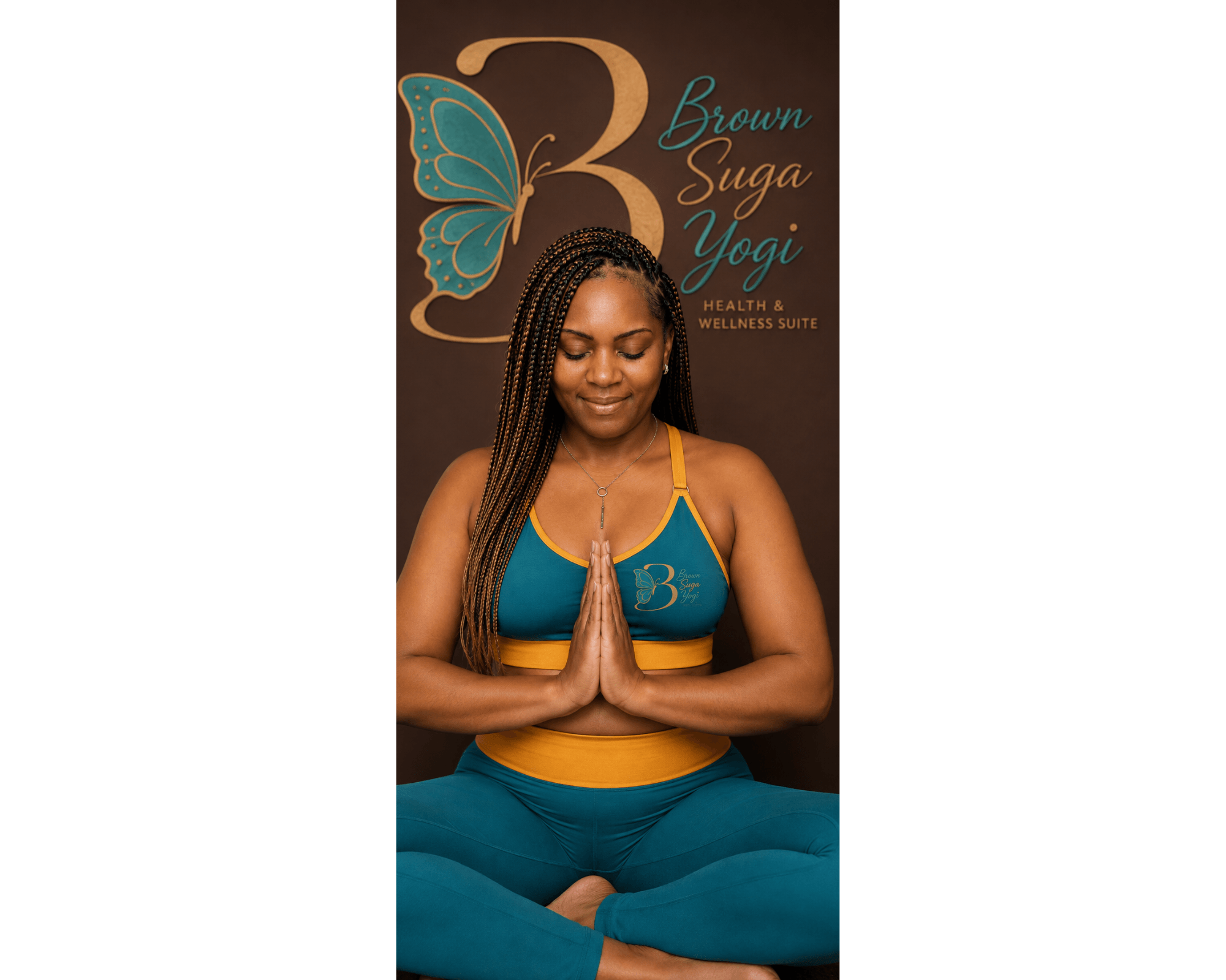 Woman practicing yoga with hands in prayer position, sitting cross-legged with eyes closed, in front of a yoga studio poster.
