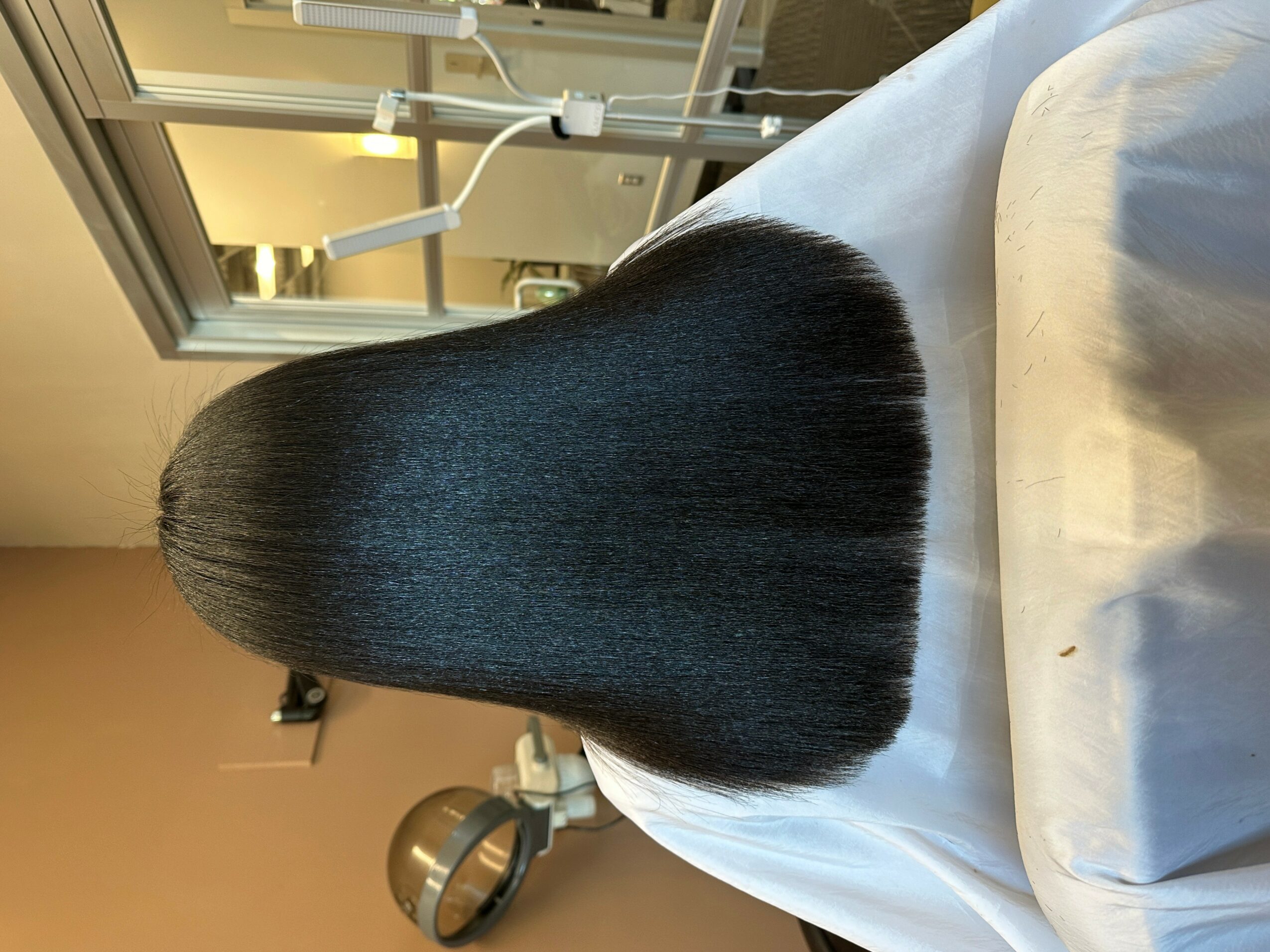 Person with straight, shiny black hair lying on a medical bed in a clinical setting.