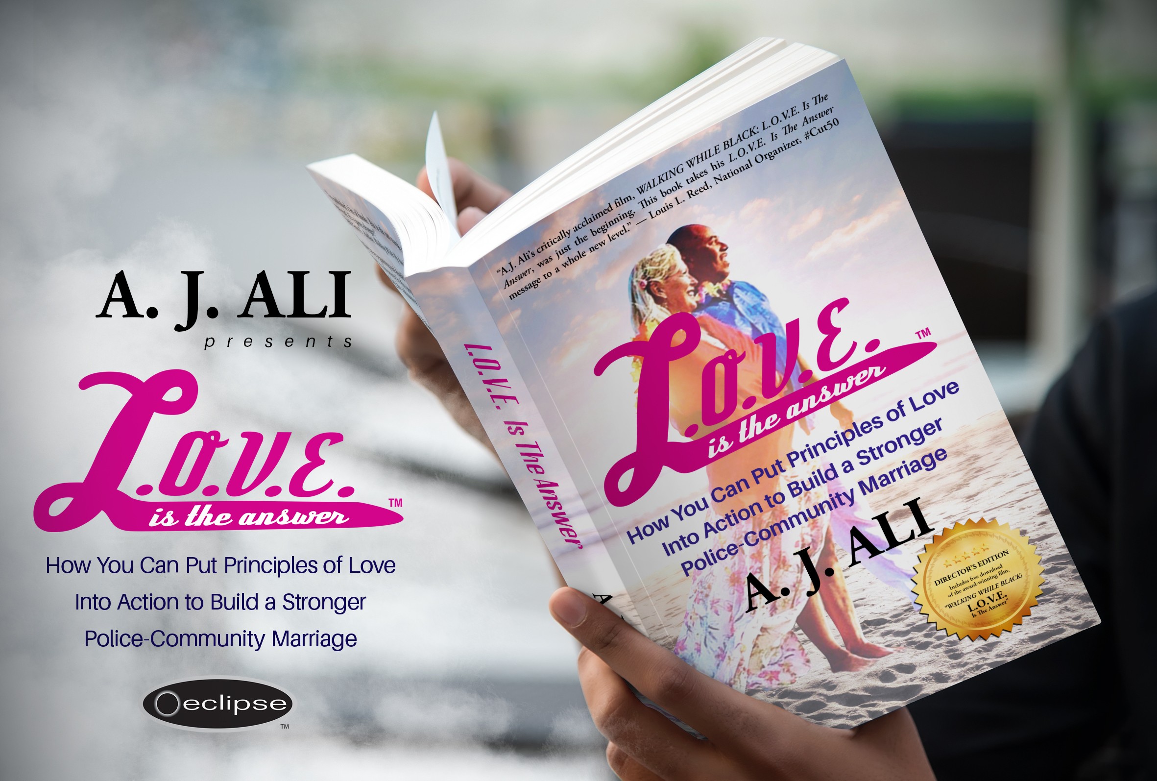 Person holding an open book titled 'Love is the Answer' with a beach scene on the cover, background blurred.