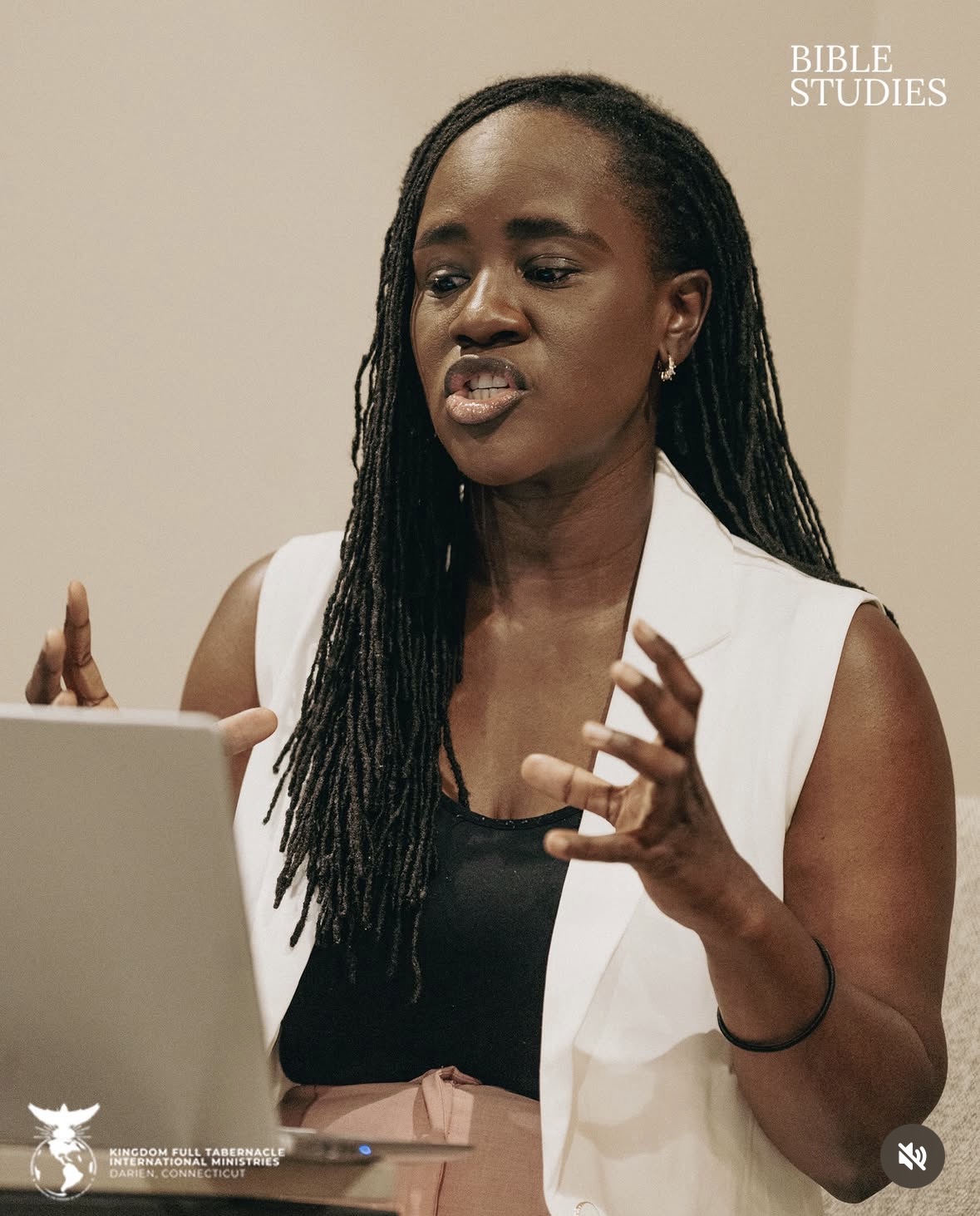 Woman speaking with hand gestures, wearing a white vest and black top, in front of a laptop, with text 'BIBLE STUDIES' in the top right.