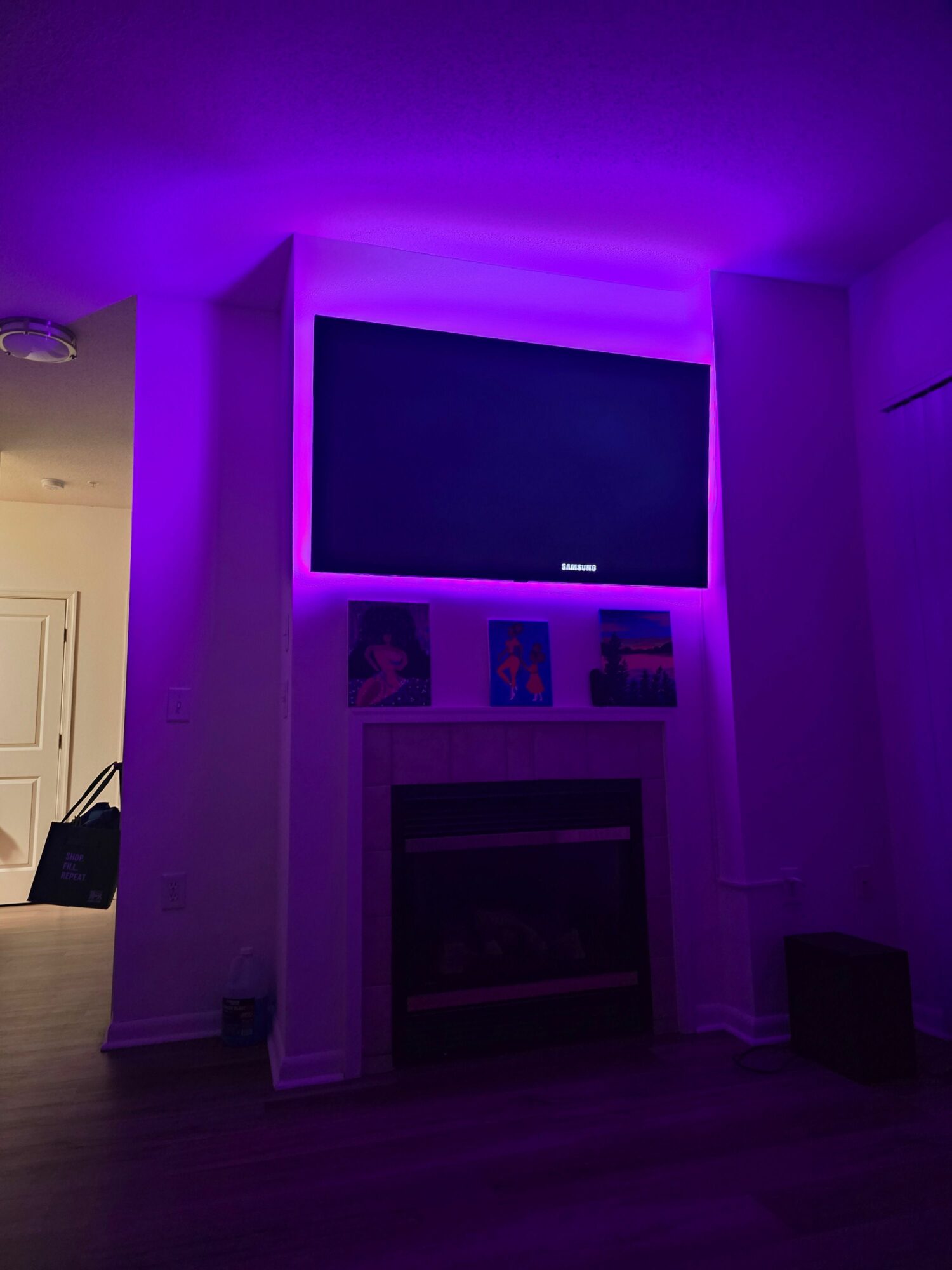 Room with purple lighting, window, and framed pictures on wall, viewed from a rotated perspective.