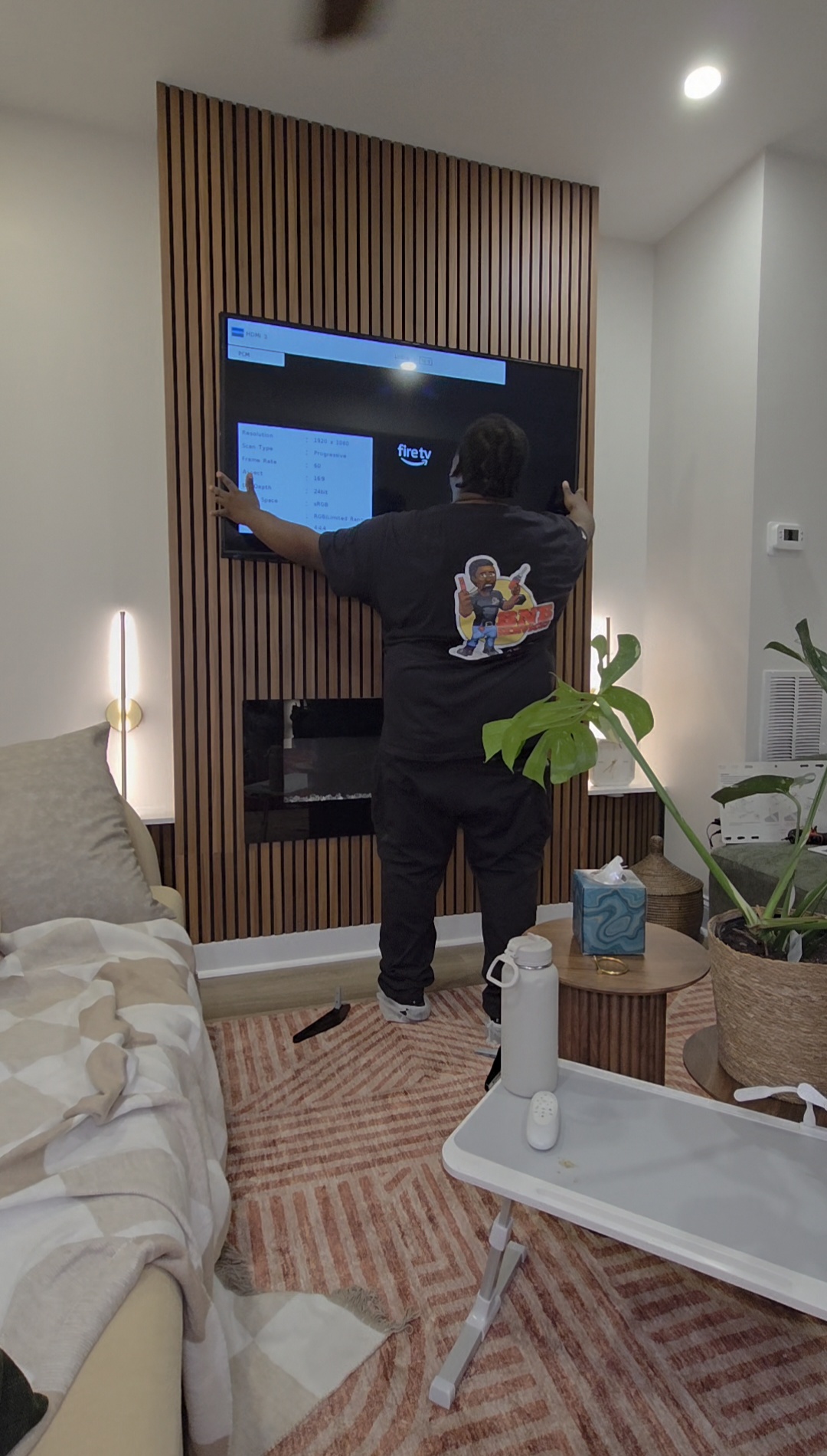 Person interacting with a large screen mounted on a wooden panel wall in a modern room with plants and furniture.