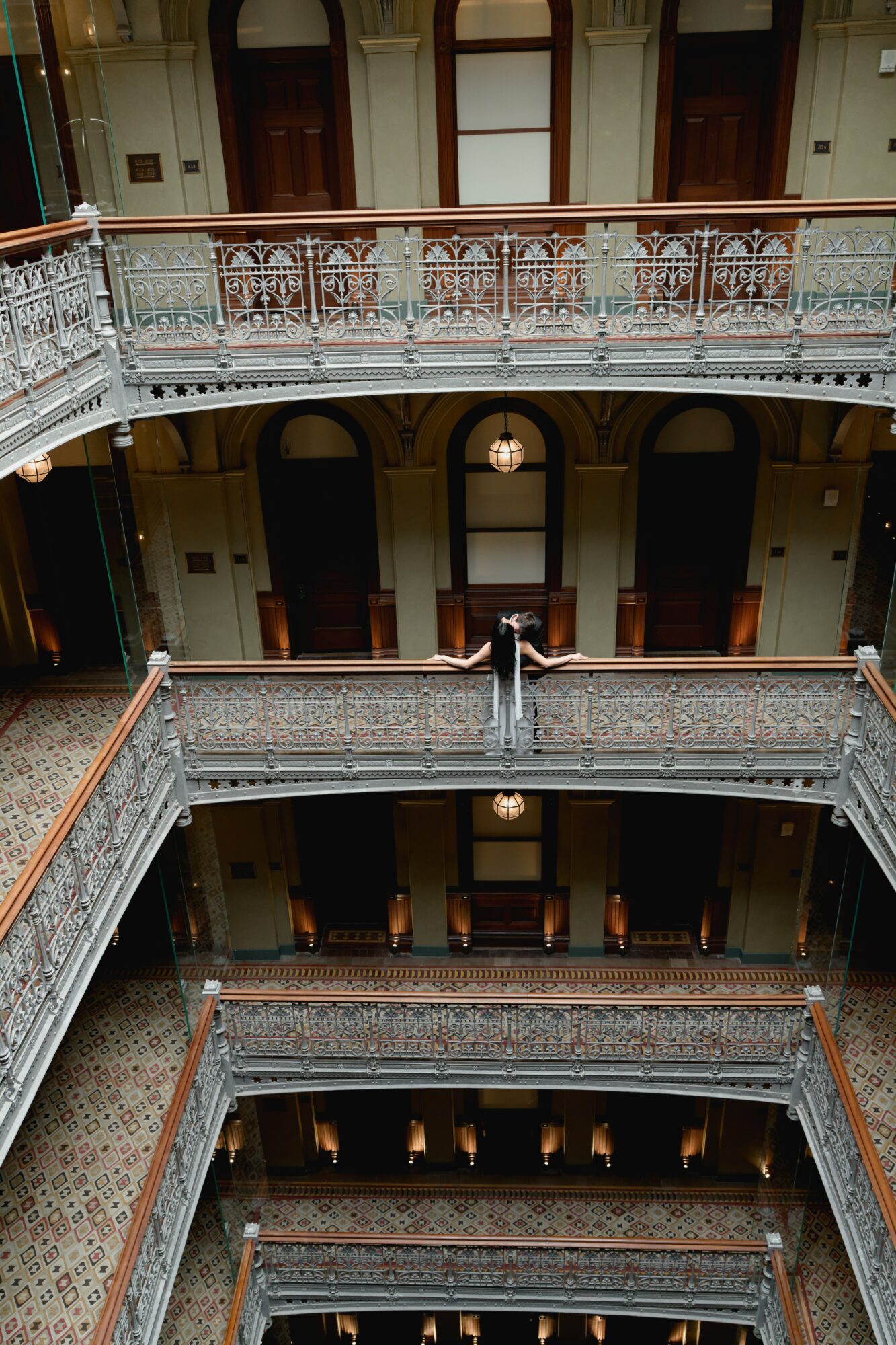 Interior view of a multi-story building with ornate railings, balconies, and a central fountain, viewed from below.