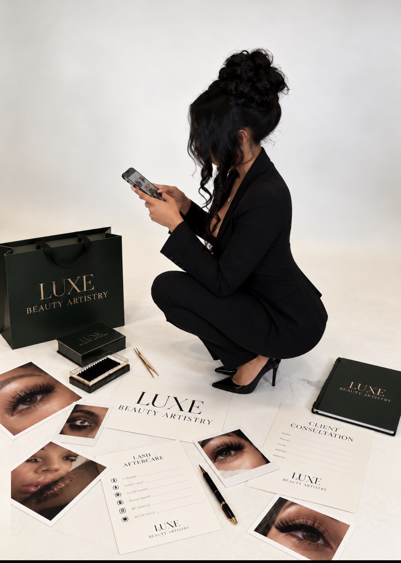Woman crouching, looking at her phone, surrounded by beauty product packaging and promotional materials, against a plain background.