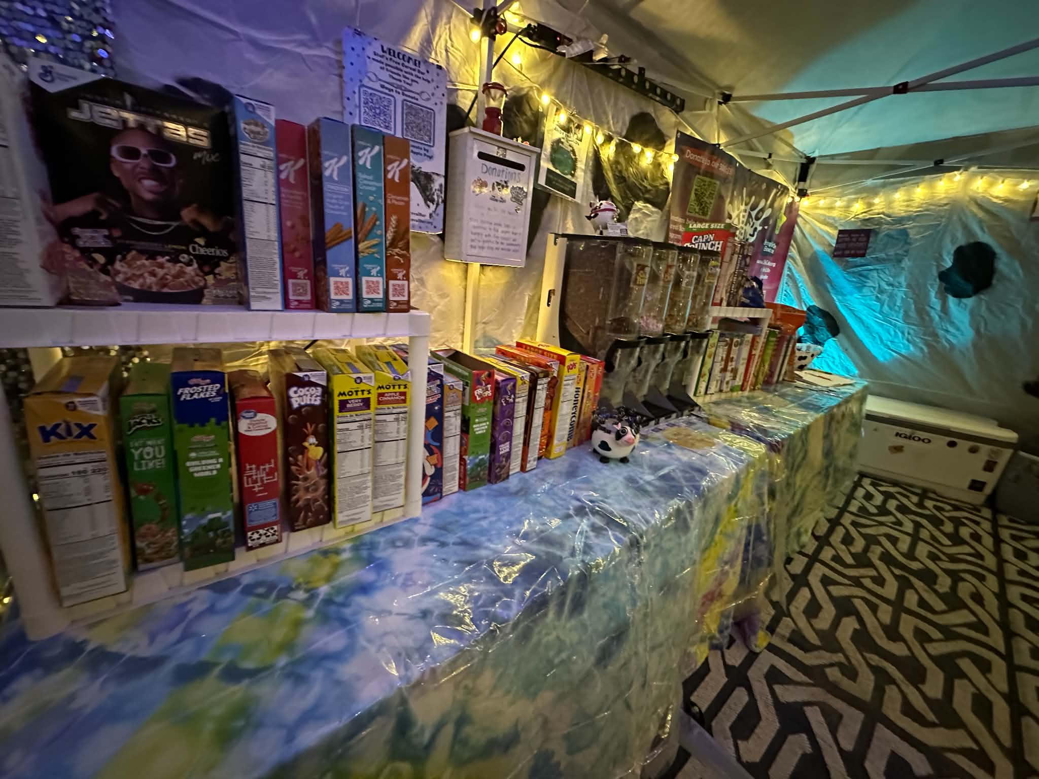 Table with snacks and toys inside a decorated tent, with string lights and patterned floor visible.