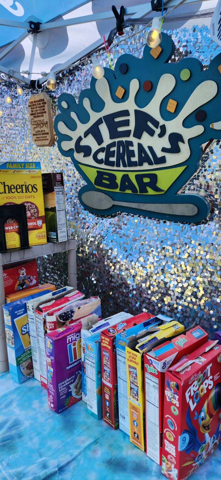 Skee Ball sign with colorful boxes of snacks and a bottle of soda on a table, with confetti and a blue tablecloth.