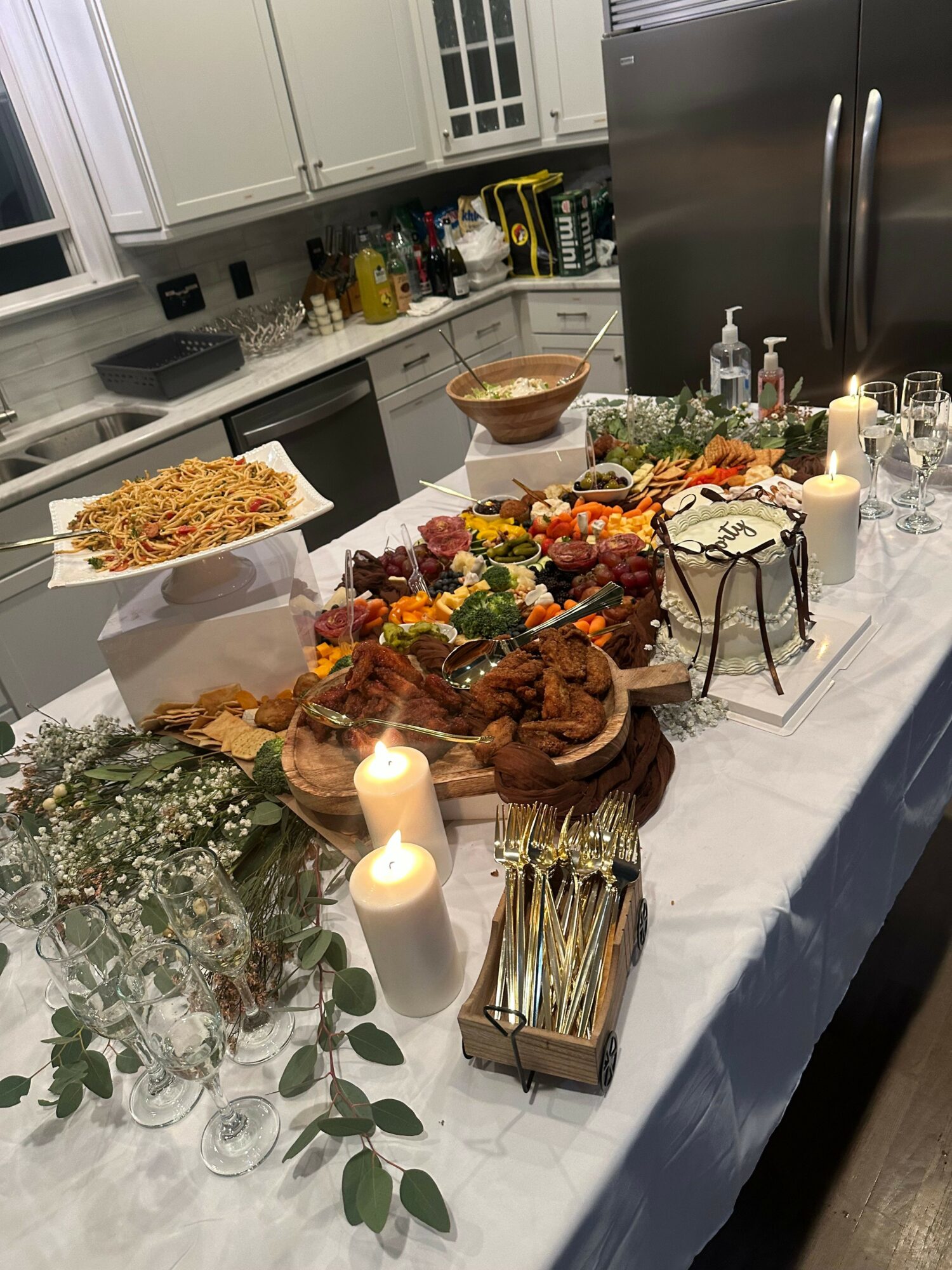 Table with food, flowers, candles, and decorations in a kitchen setting.